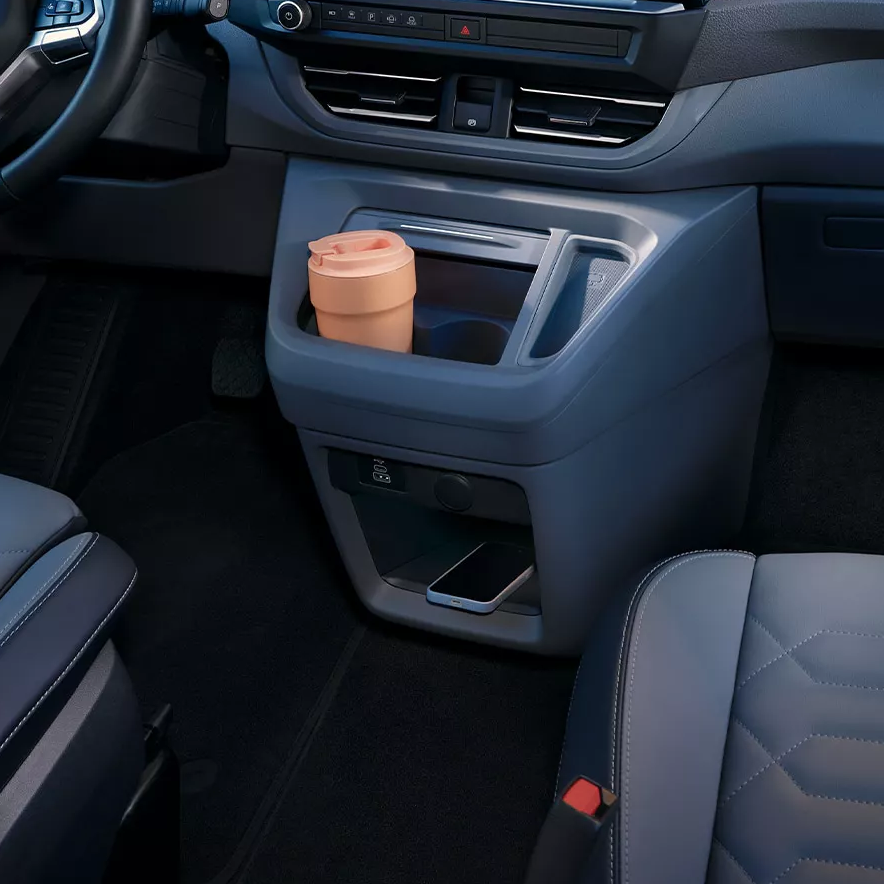 Интериор на Volkswagen Caravelle с модерен кокпит и дигитален дисплей, паркиран пред хотел