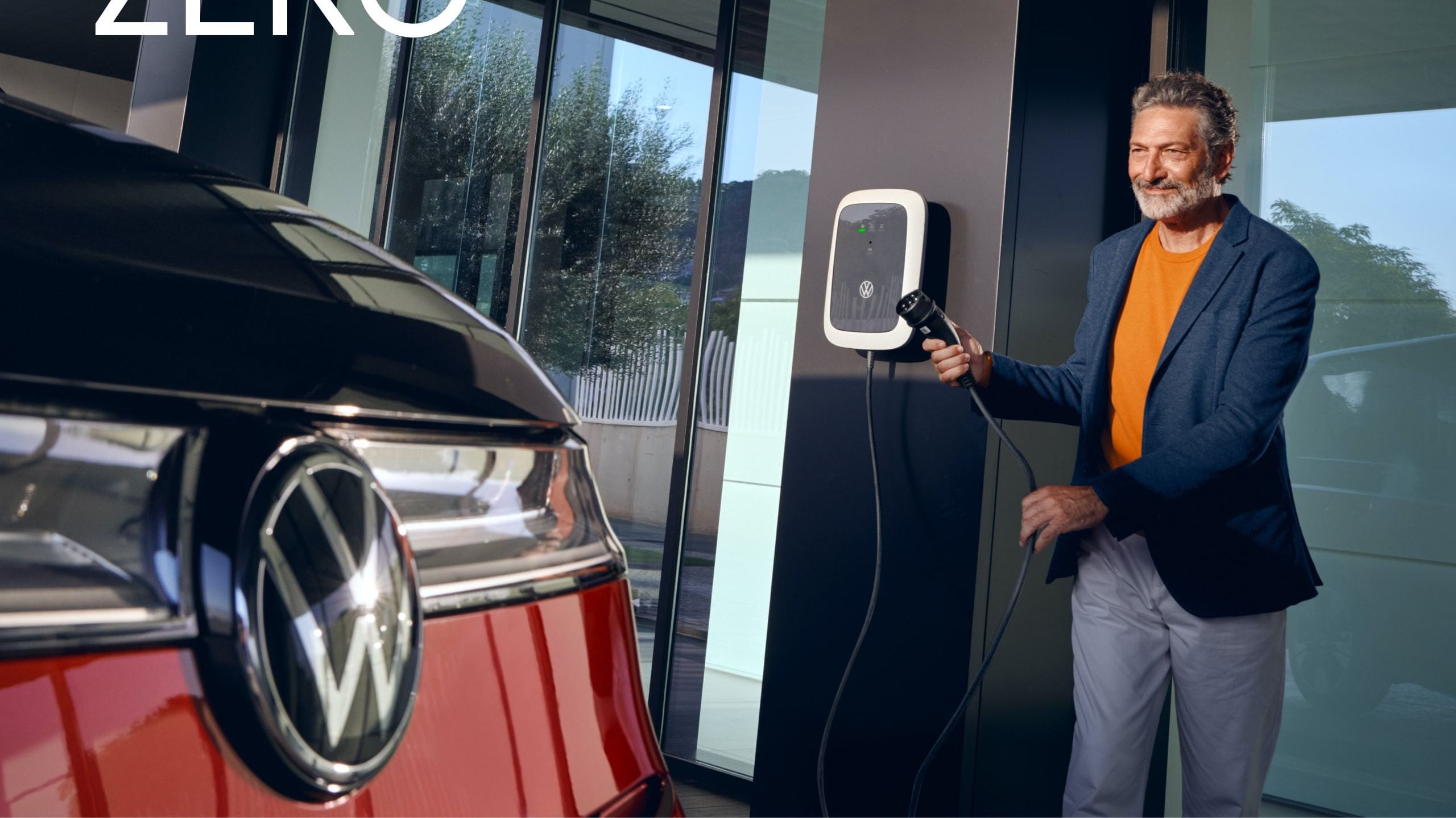Ein Mann steht an einer Ladesäule neben einem neuen VW Multivan T7 2021.