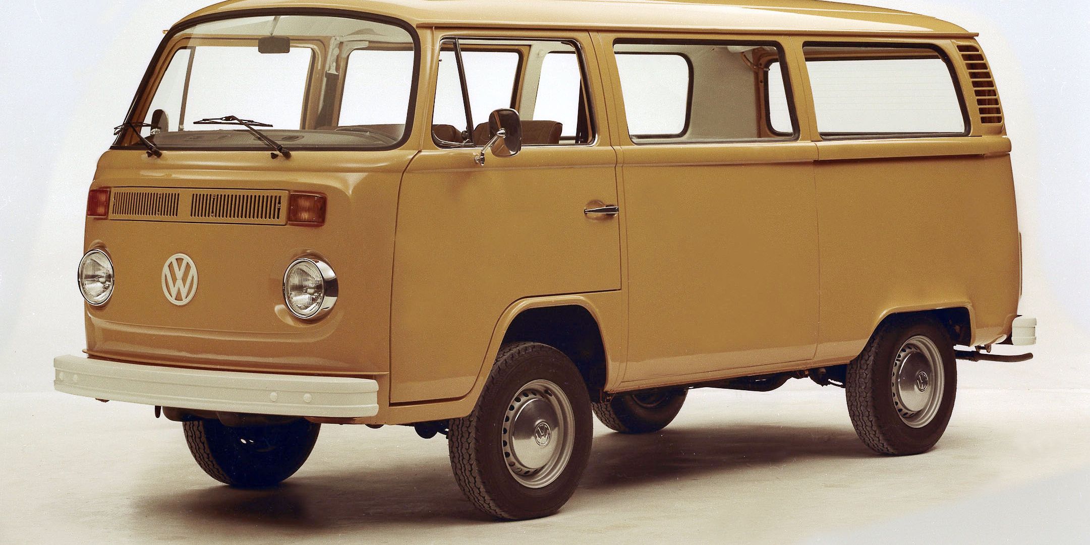 Ретро микробус Volkswagen с бяла броня и две врати отстрани. Микробусът е сниман на светъл фон. Той е модел от около 70-те години.