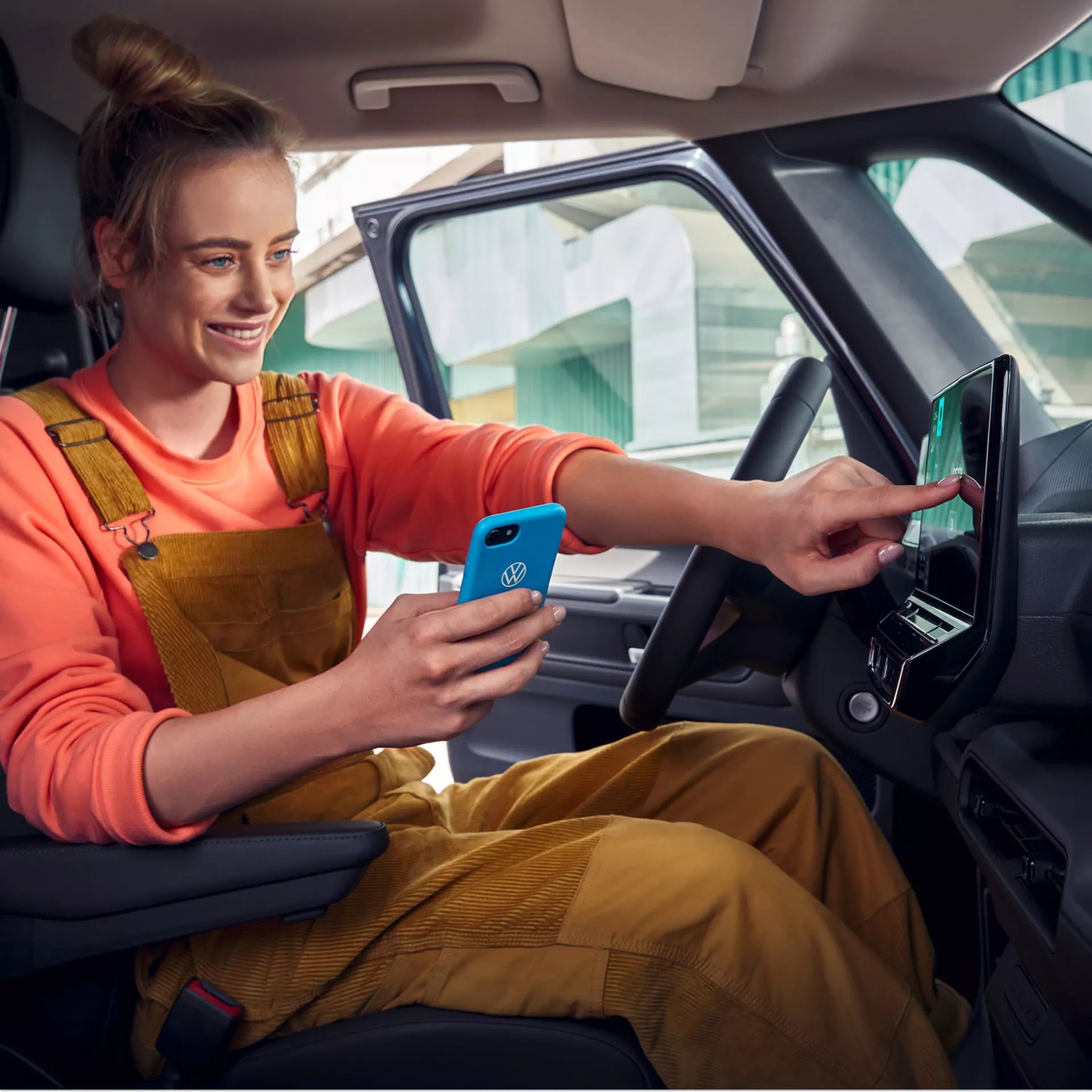 Млада жена управлява инфотейнмънт системата на Volkswagen чрез смартфон с логото на марката
