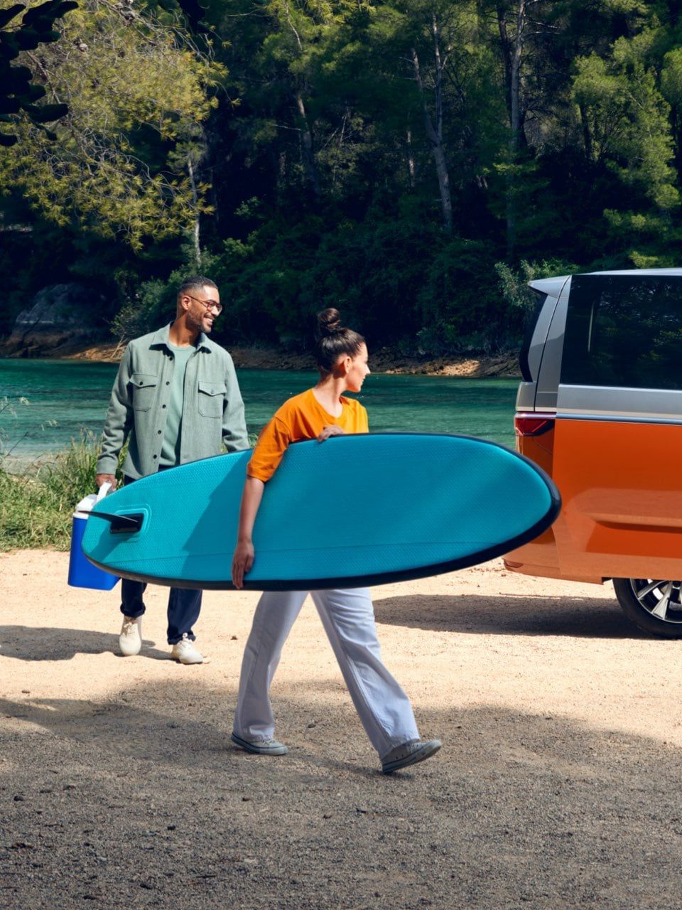 Ein neuer VW Multivan T7 2021 Energetic eHybrid parkt vor einem Fluss und Menschen laufen um ihn herum.