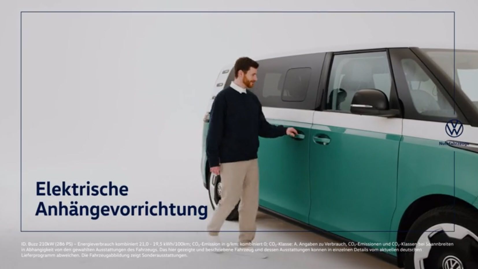 Мъж до двуцветен Volkswagen ID. Buzz с надпис „Elektrische Anhängevorrichtung“ (електрическо теглично устройство)