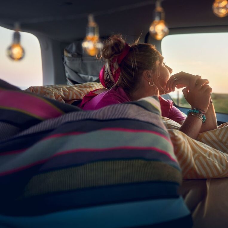 Ein VW Caddy 2020 parkt vor einer Brücke. Eine Familie geht gerade vom Auto weg.