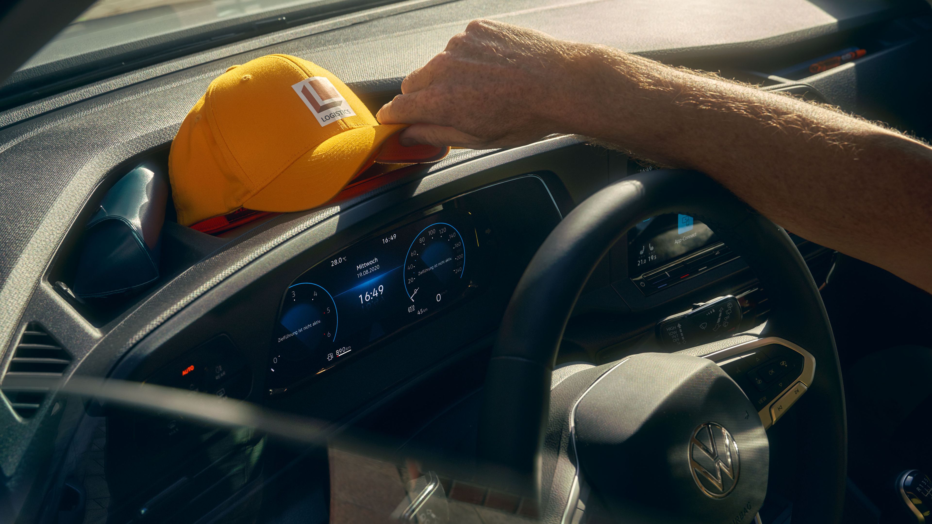 Мъж поставя шапката си в отделението за вещи върху арматурното табло на VW Caddy Cargo.