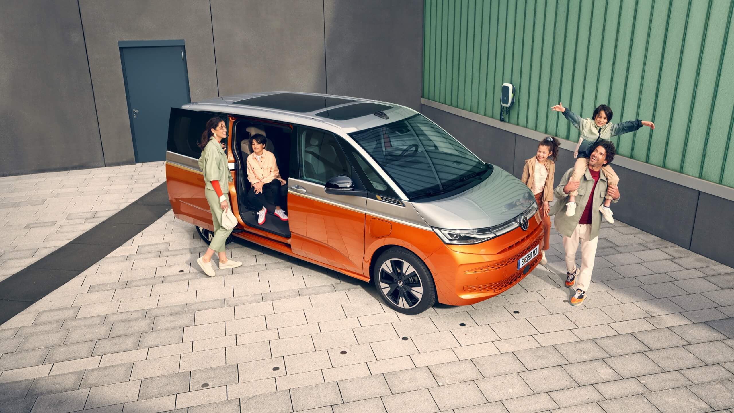 Eine Familie läuft vergnügt neben den stehenden VW Multivan T7 2021 Energetic her. 