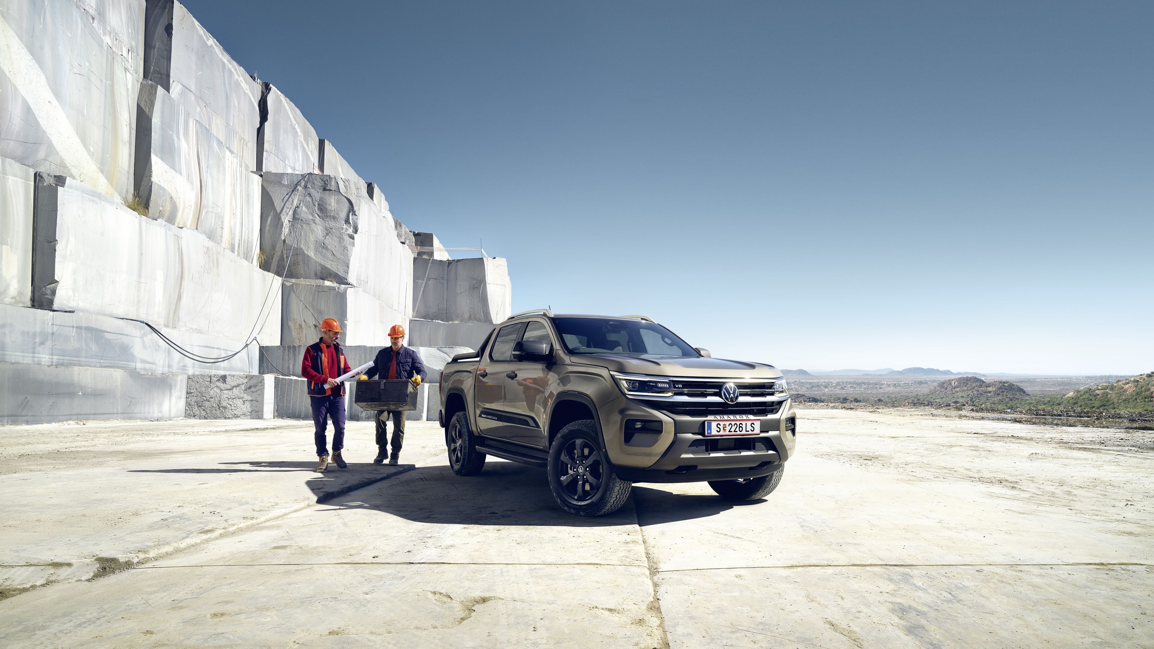 Двама работници стоят до новия VW Amarok