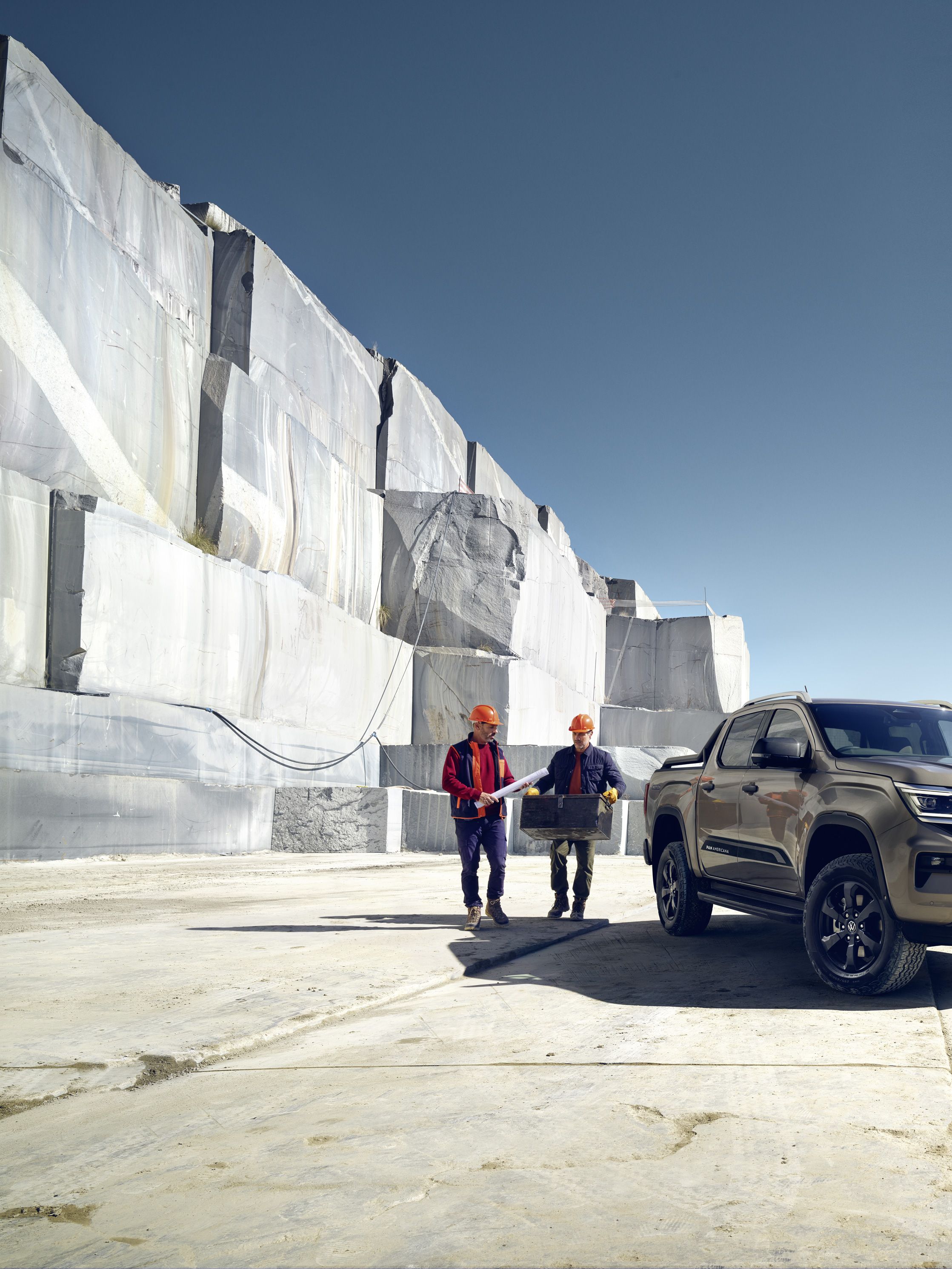 Двама работници стоят до новия VW Amarok
