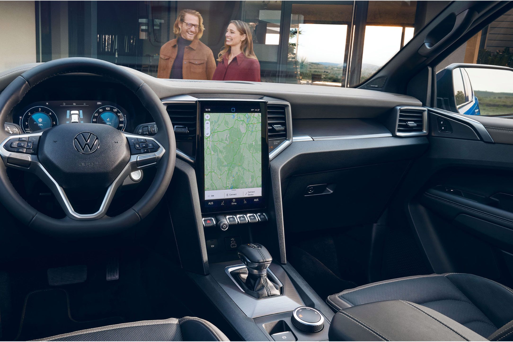 Модерен кокпит на Volkswagen с дигитален дисплей и навигационна система, с двама души отвън пред автомобила