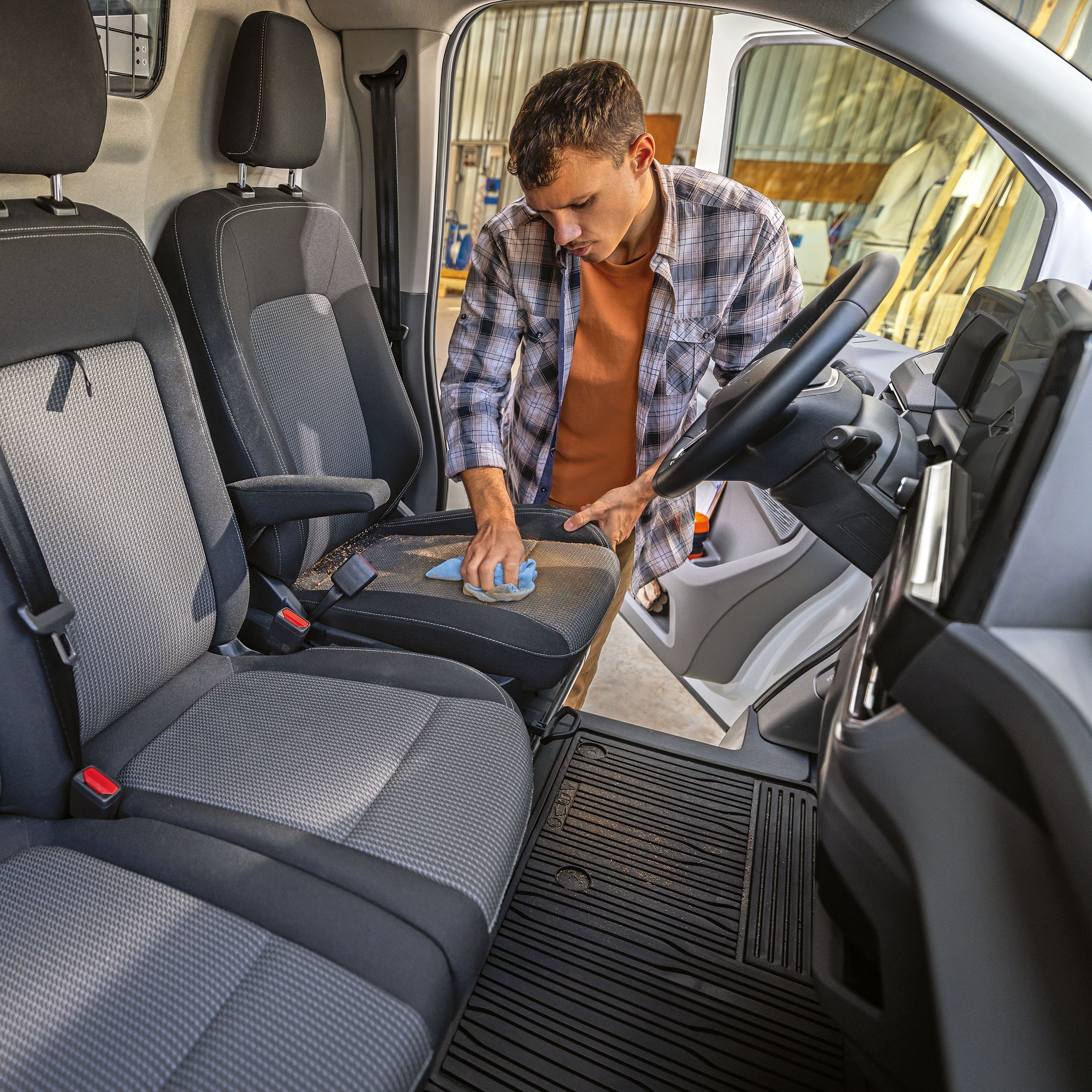 Мъж почиства седалката във вътрешността на Volkswagen e-Transporter с кърпа.