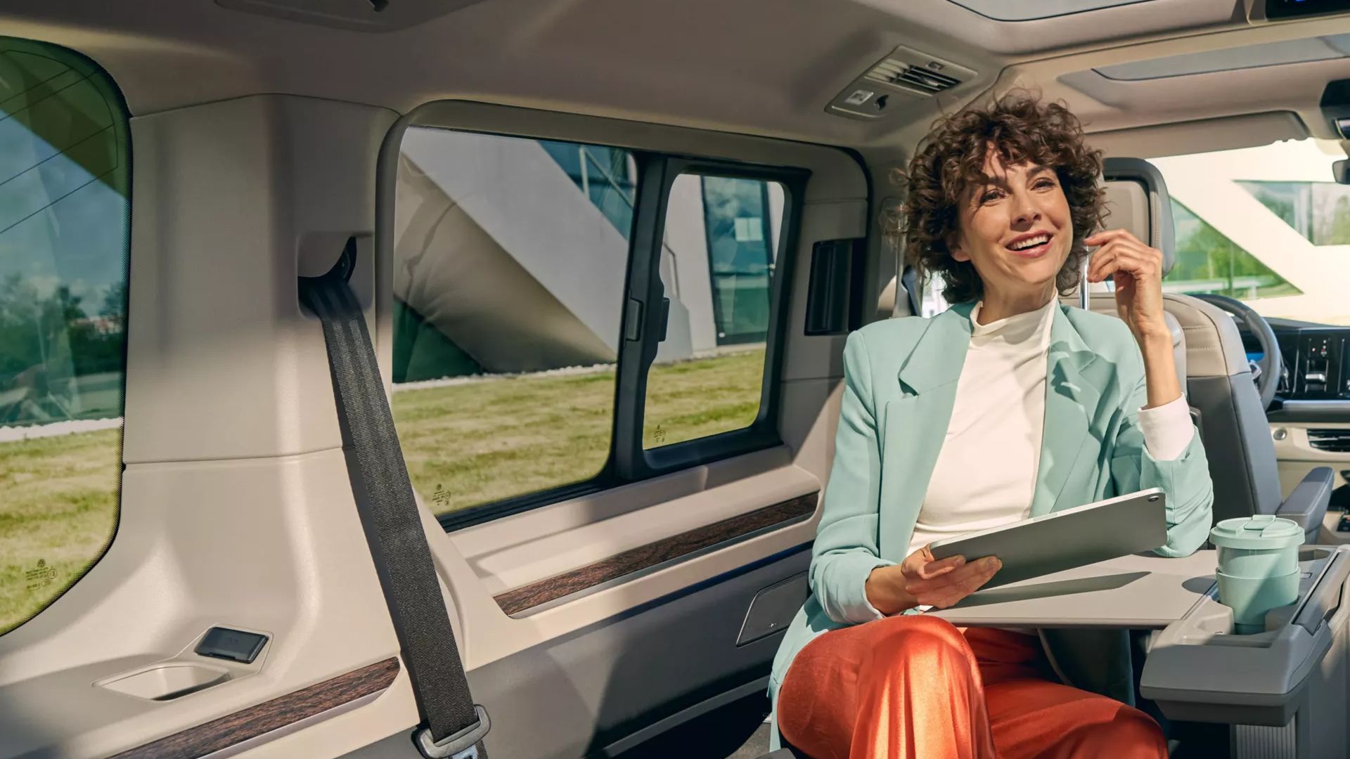 Frau sitzt im Fond eines VW Multivan und nutzt den ausklappbaren Tisch