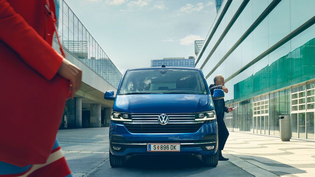 VW Multivan преминава пешеходна пътека. Жена с жълта горна дреха пресича пешеходната пътека.
