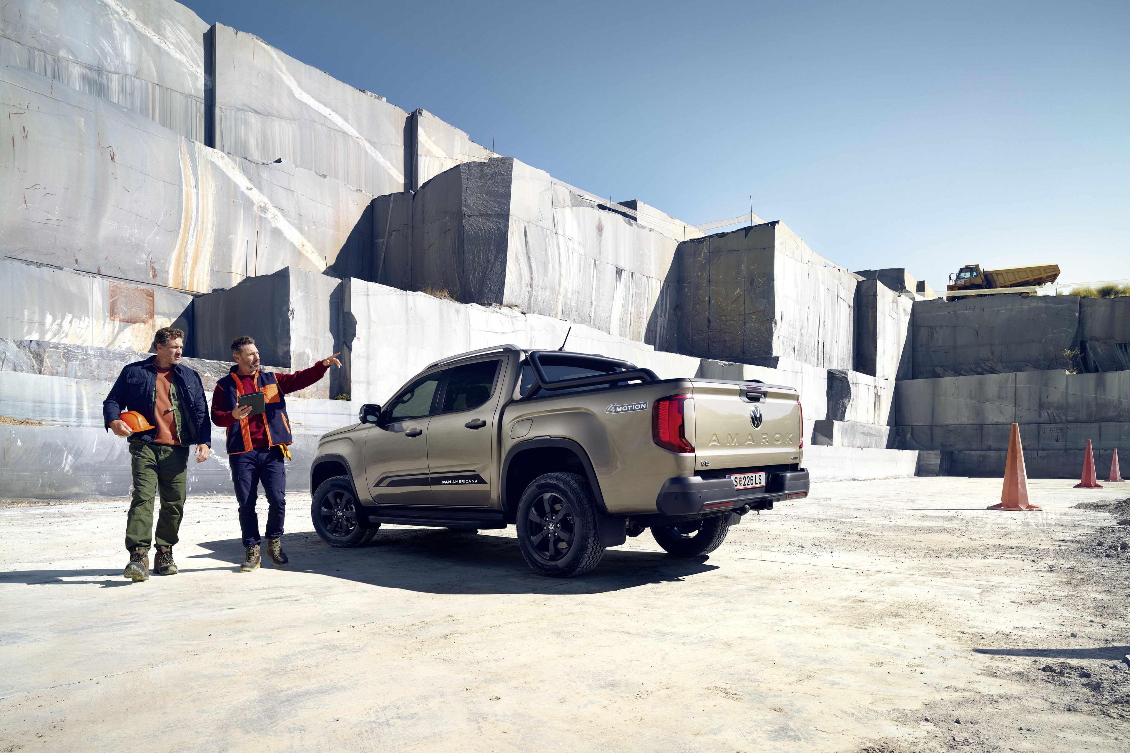 Volkswagen Amarok с двама мъже в работна екипировка на строителен обект с каменни блокове