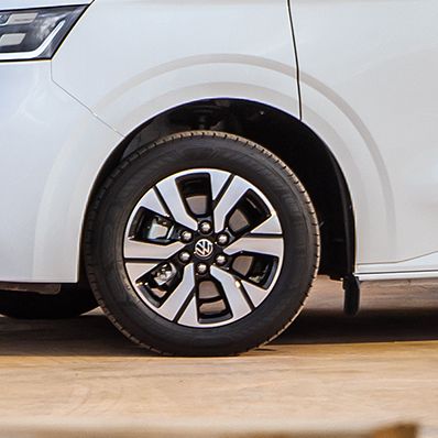 Електрически ван Volkswagen e-Transporter на строителен обект с двама работници, носещи инструменти и материали.