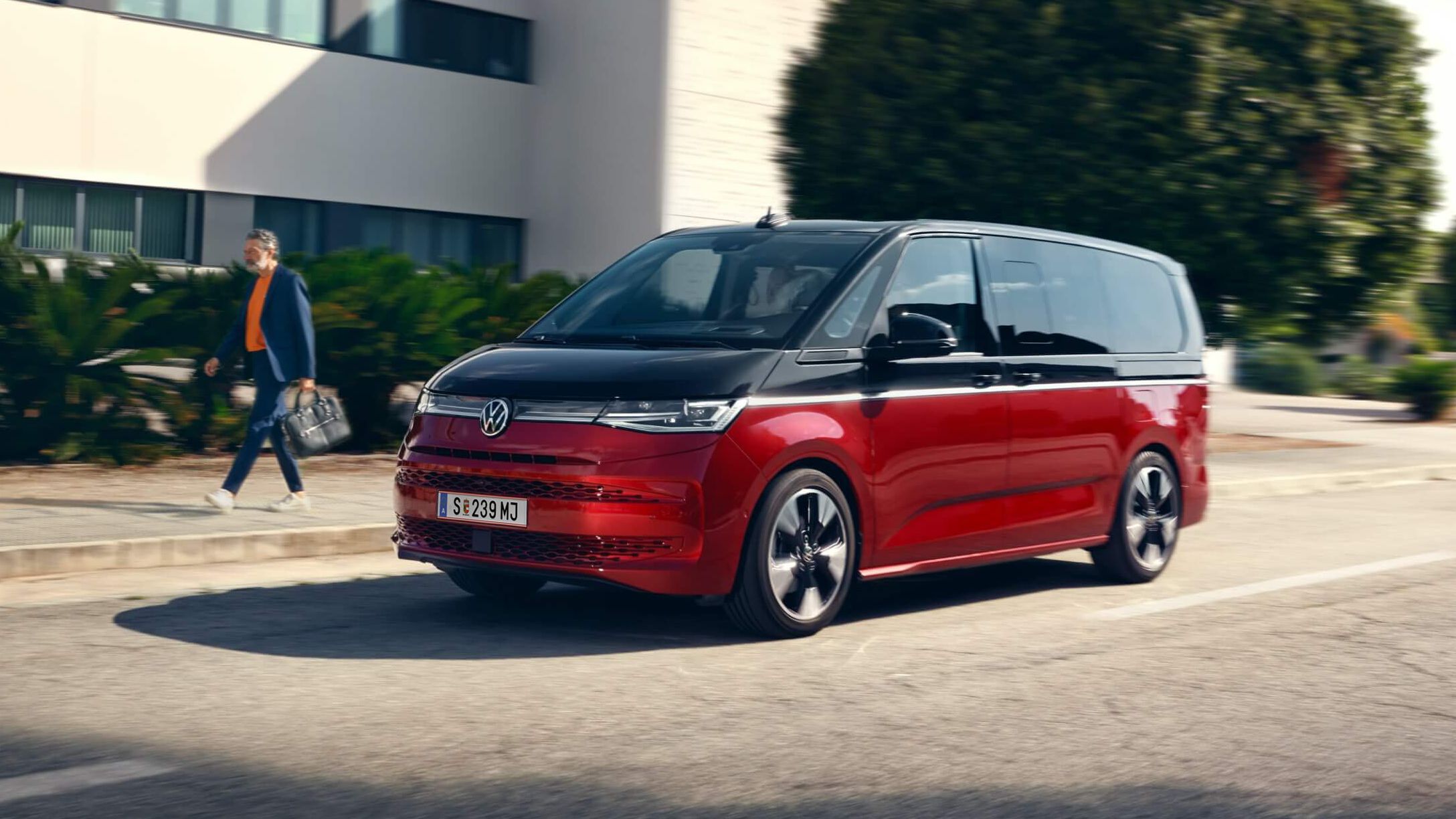 Новият Volkswagen Multivan в червено-черна двуцветна комбинация на улица