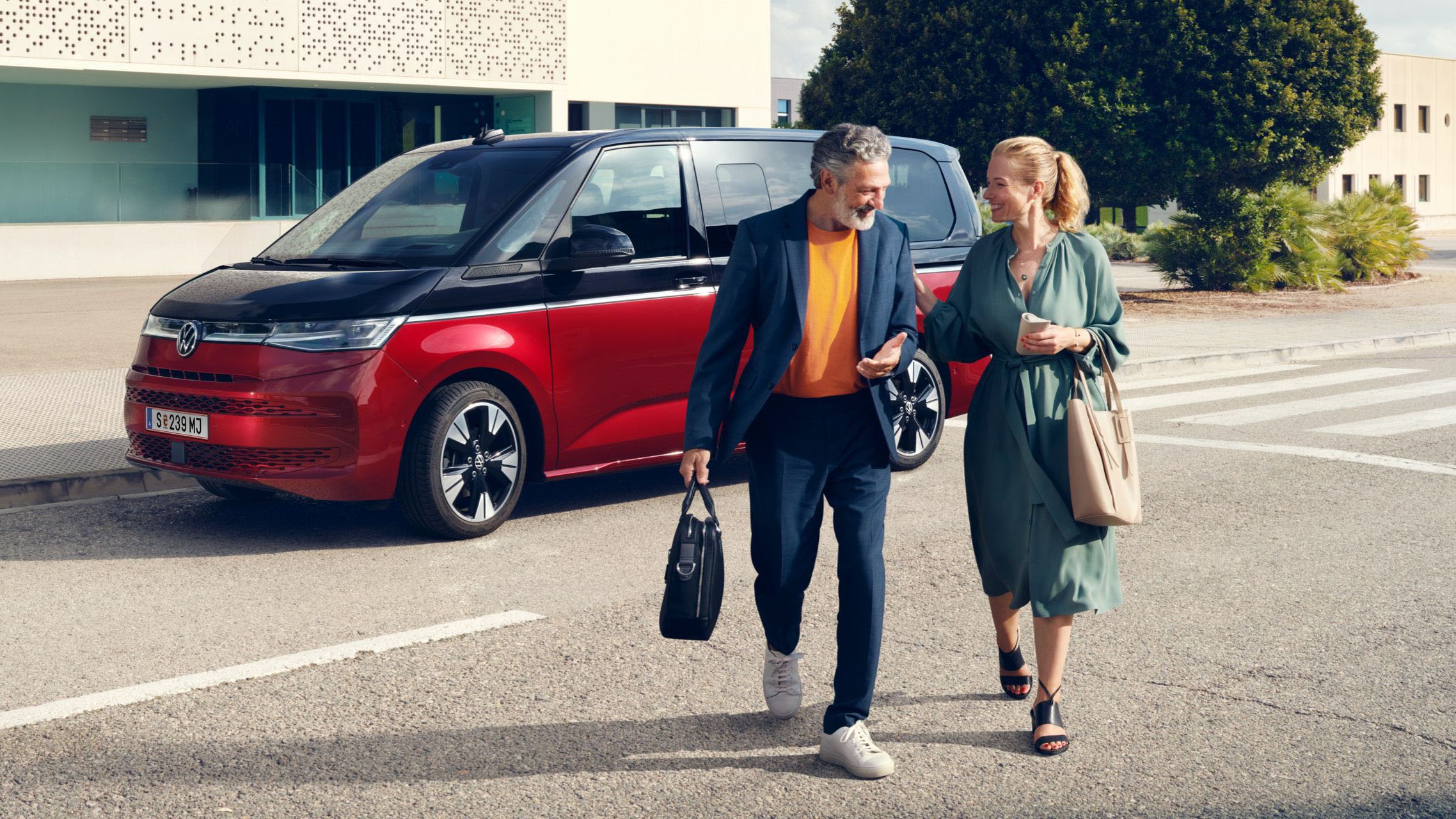 Ein Paar läuft vor dem neuen VW Multivan T7 2021 Style.