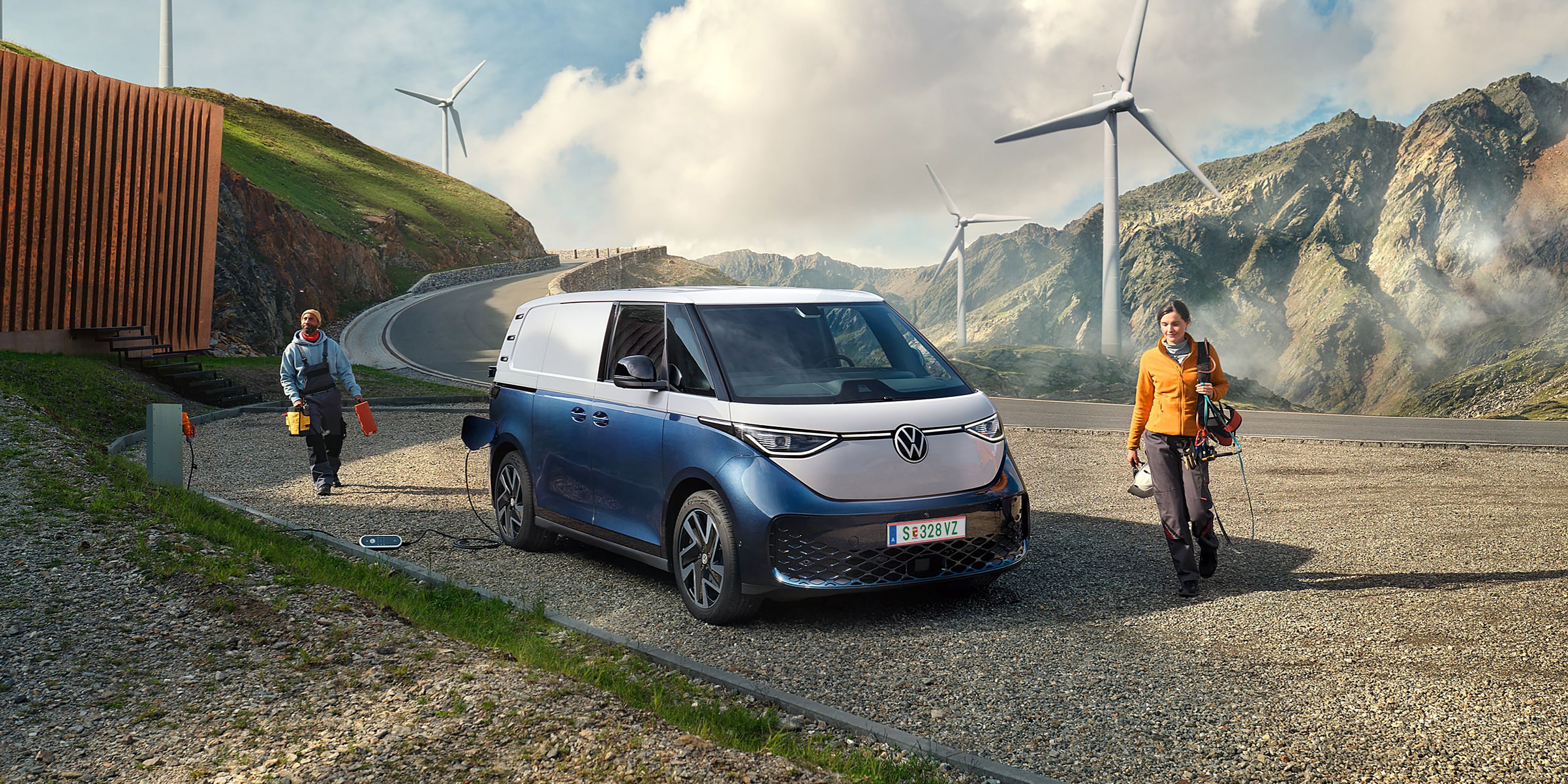 Volkswagen ID. Buzz Cargo в процес на зареждане сред вятърни турбини и планински пейзаж