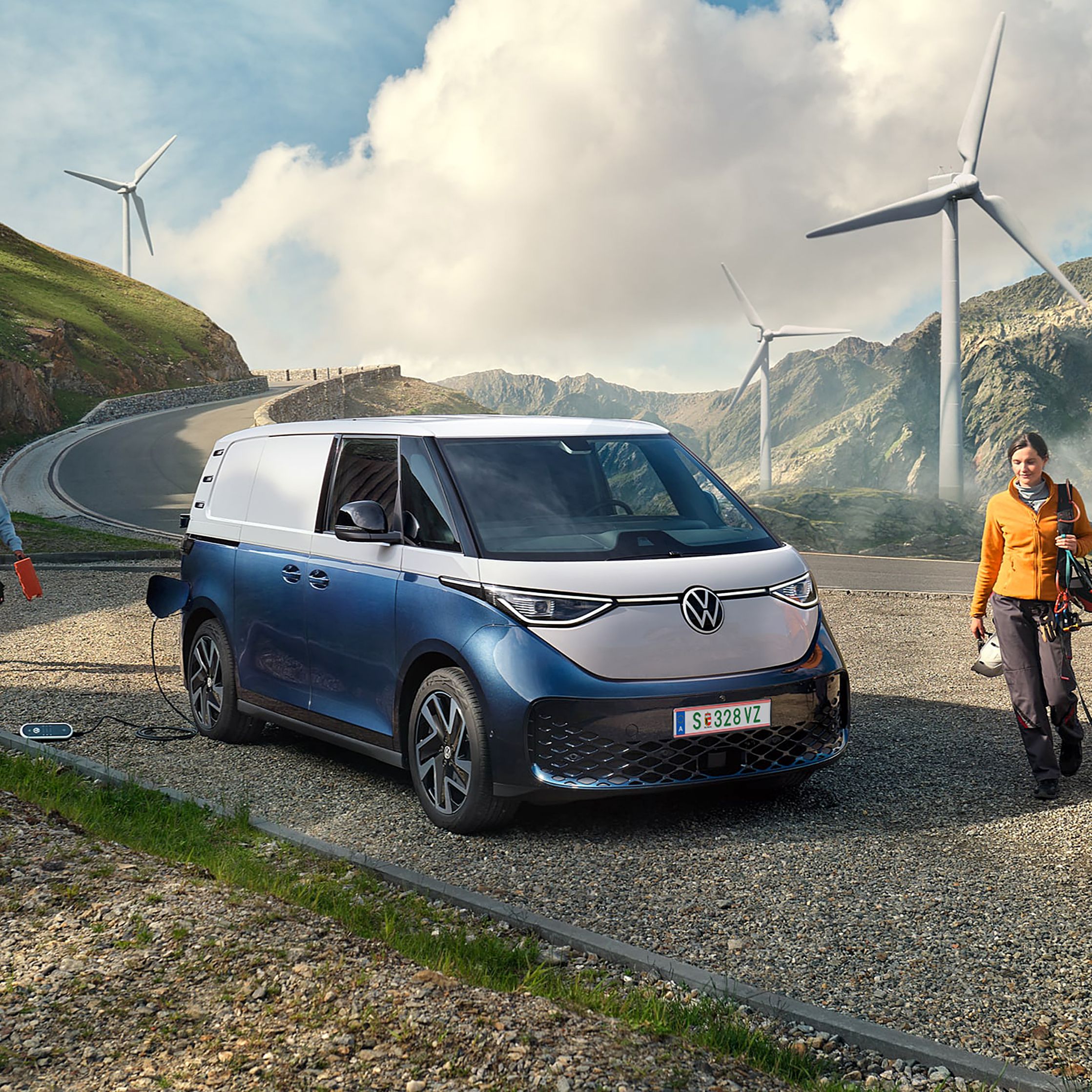 Volkswagen ID. Buzz Cargo в процес на зареждане сред вятърни турбини и планински пейзаж