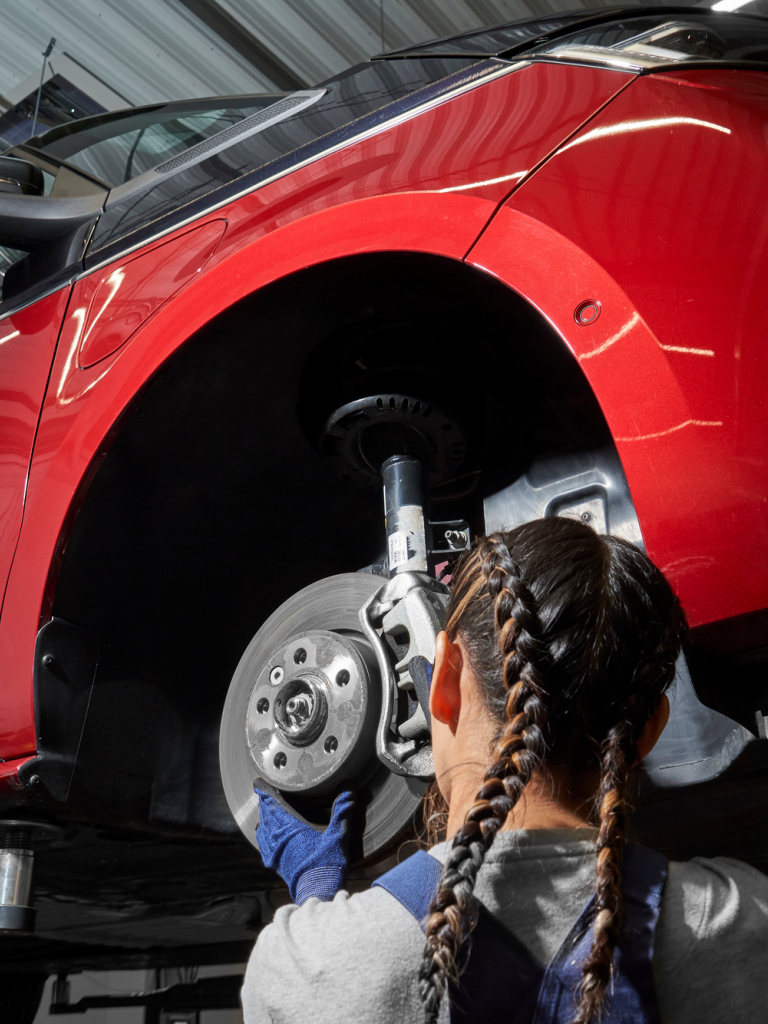Eine VW Mechanikerin wechselt die Bremsscheiben bei einem VW Nutzfahrzeug