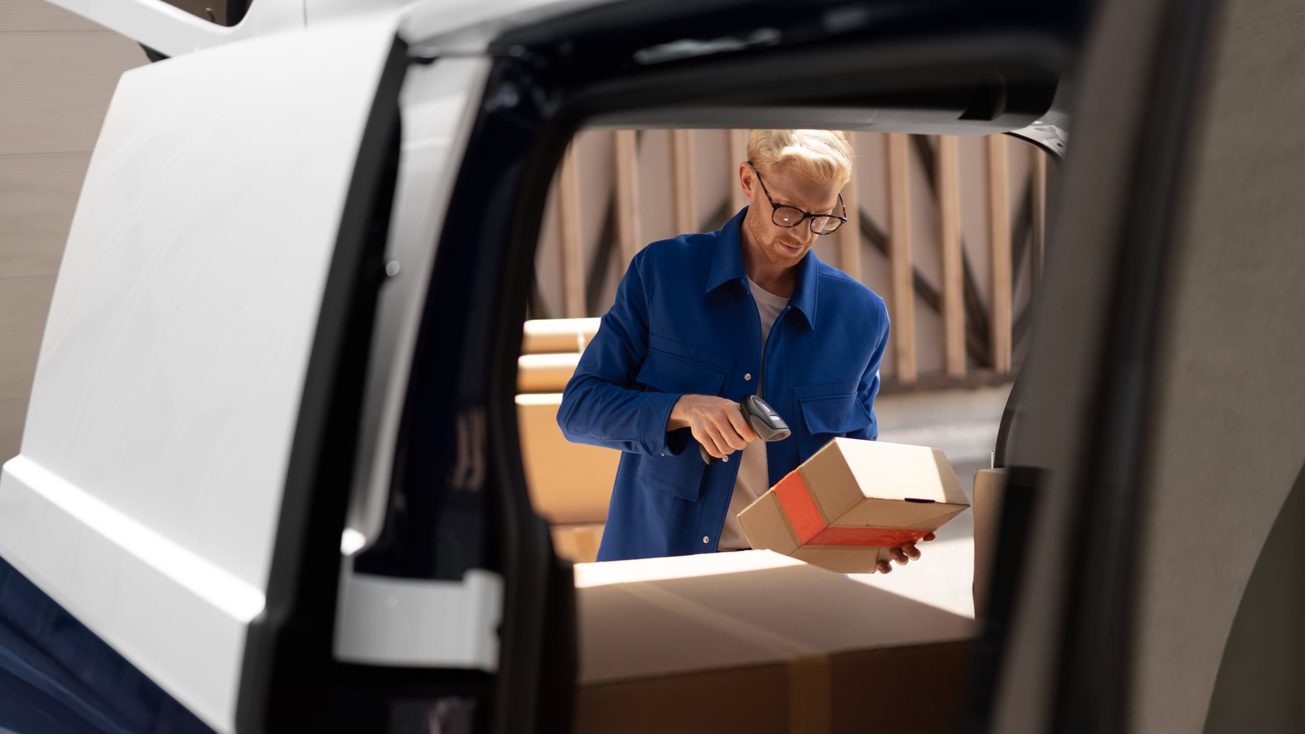 Мъж сканира пратка в товарното пространство на електрическия Volkswagen ID. Buzz Cargo.