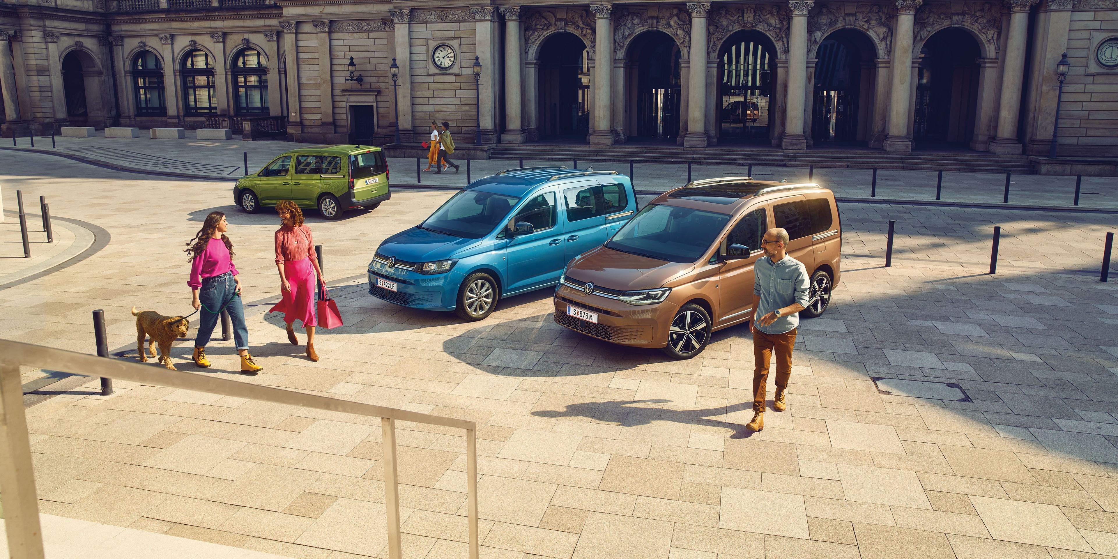 Три автомобила VW Caddy в различни цветове в градска среда.
