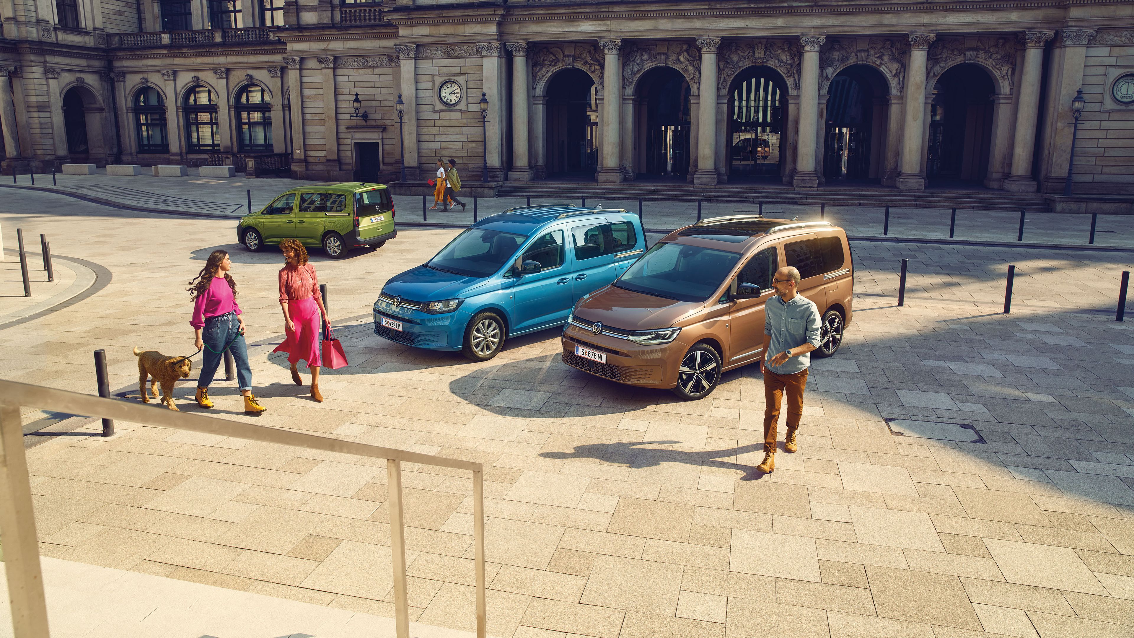 Три автомобила VW Caddy в различни цветове в градска среда.