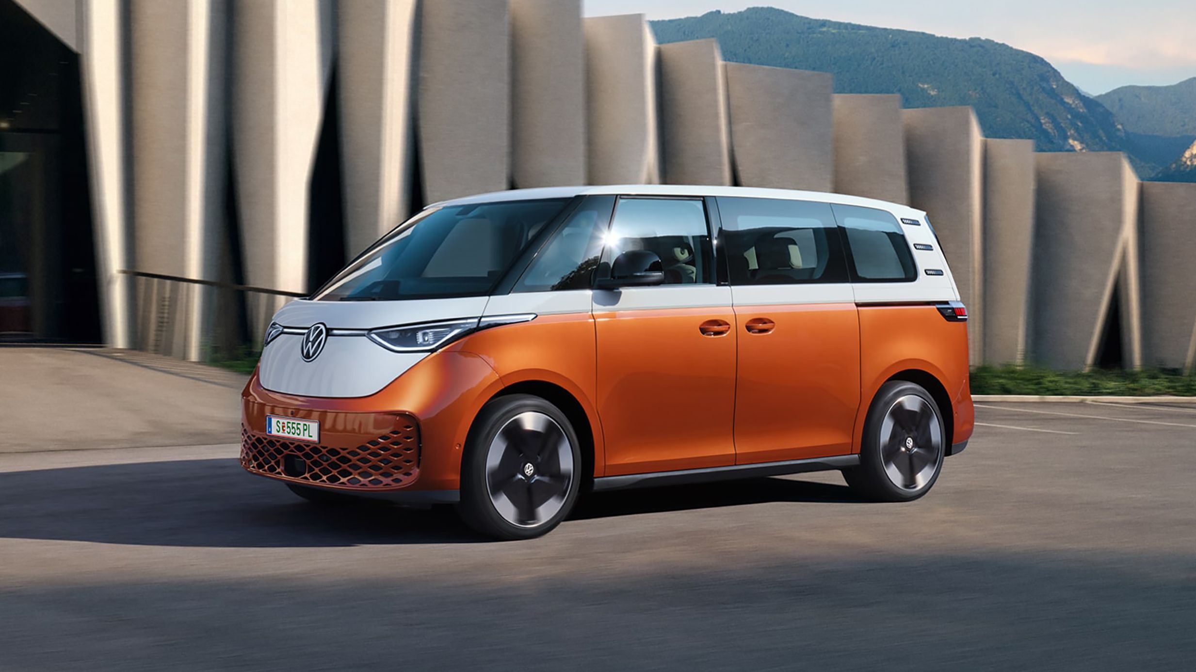 Volkswagen ID. Buzz в движение пред модерна архитектура и планински фон