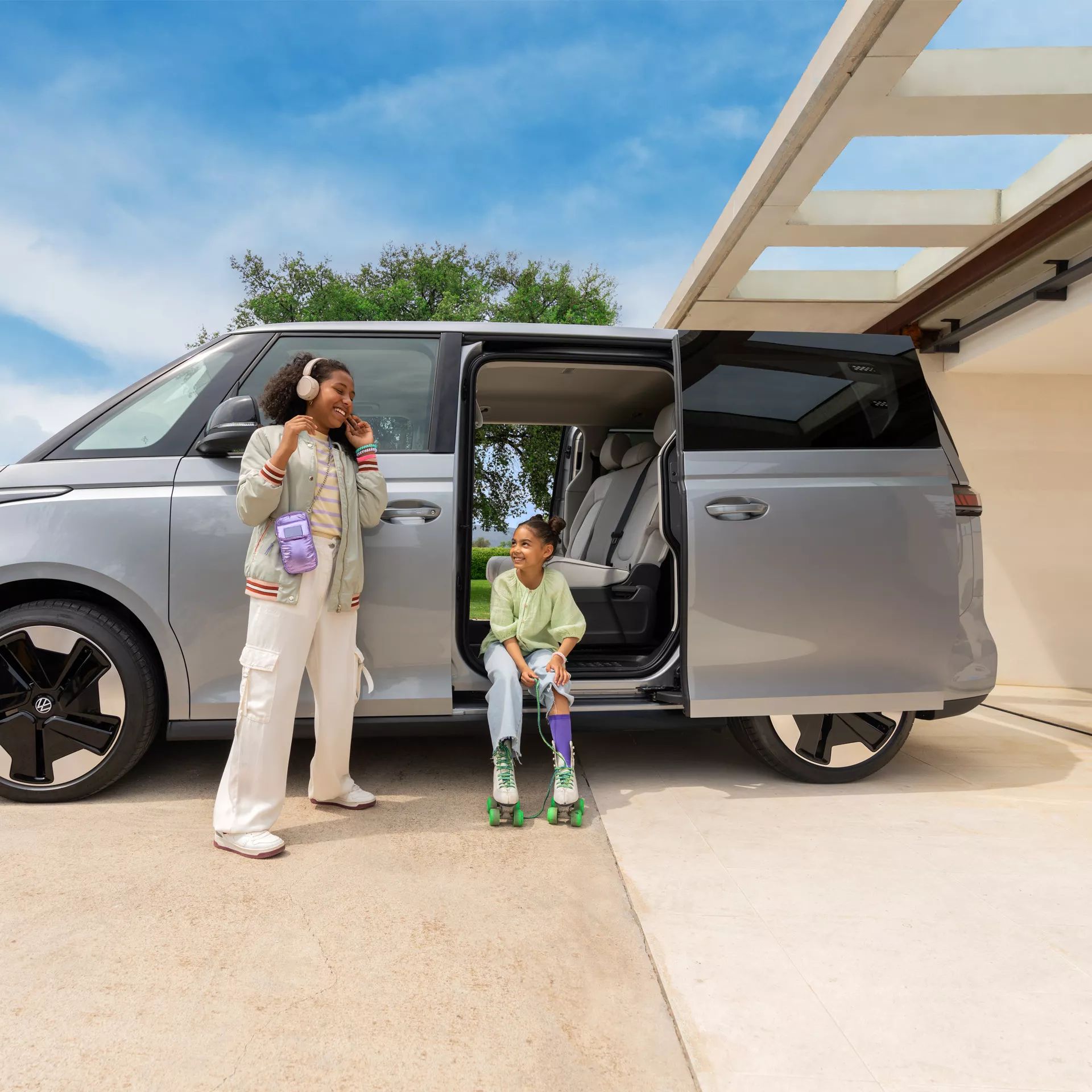 Две момичета се наслаждават на момент пред електрическия Volkswagen ID. Buzz с отворена плъзгаща се врата
