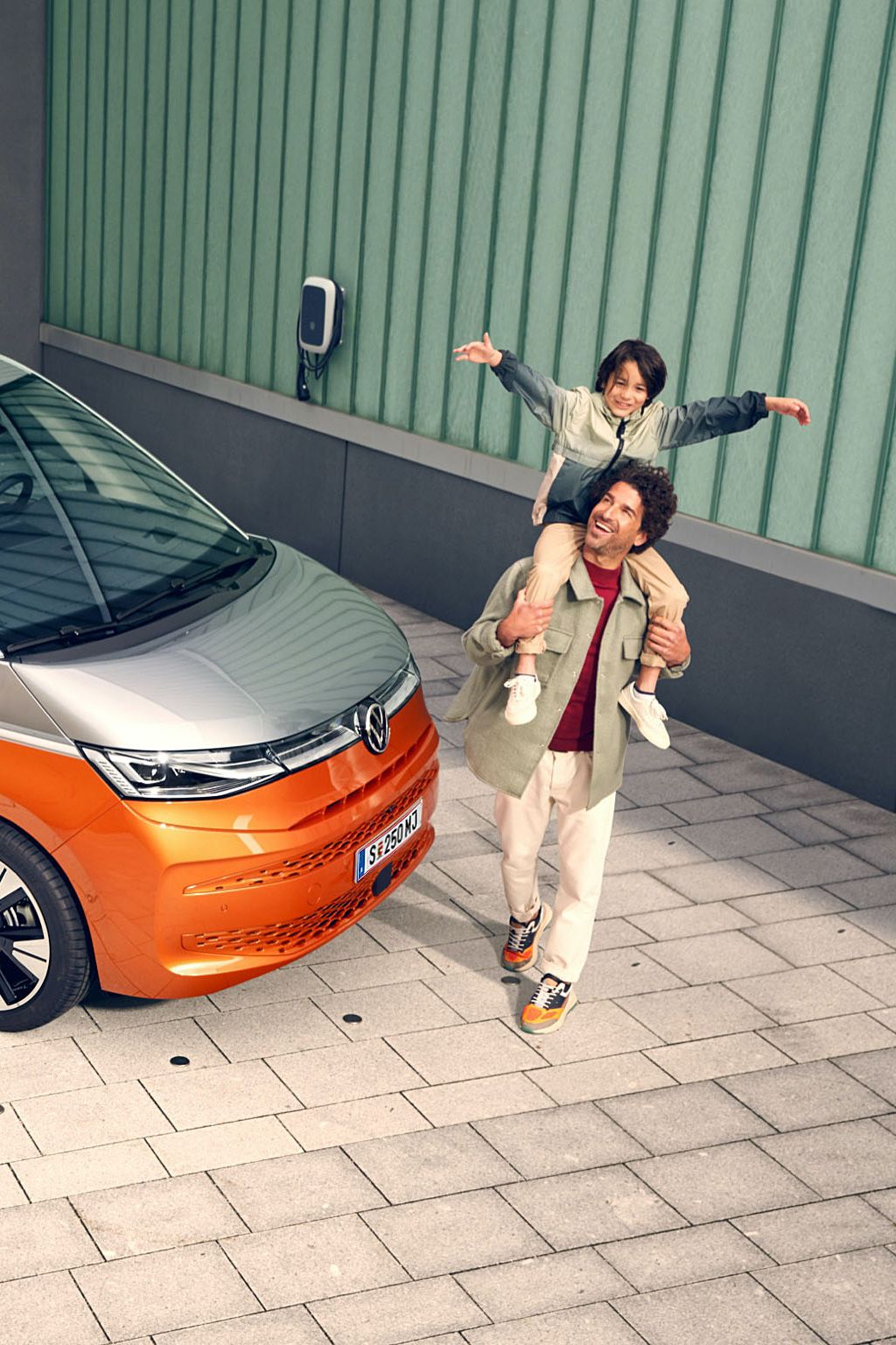 Eine Familie läuft vergnügt neben dem stehenden VW Multivan Energetic T7 2021 her