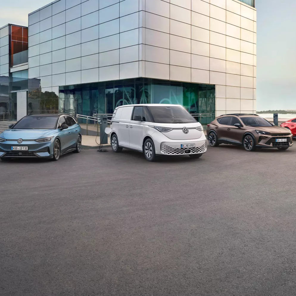Гама електрически автомобили от Volkswagen и Audi, паркирани пред модерна бизнес сграда.