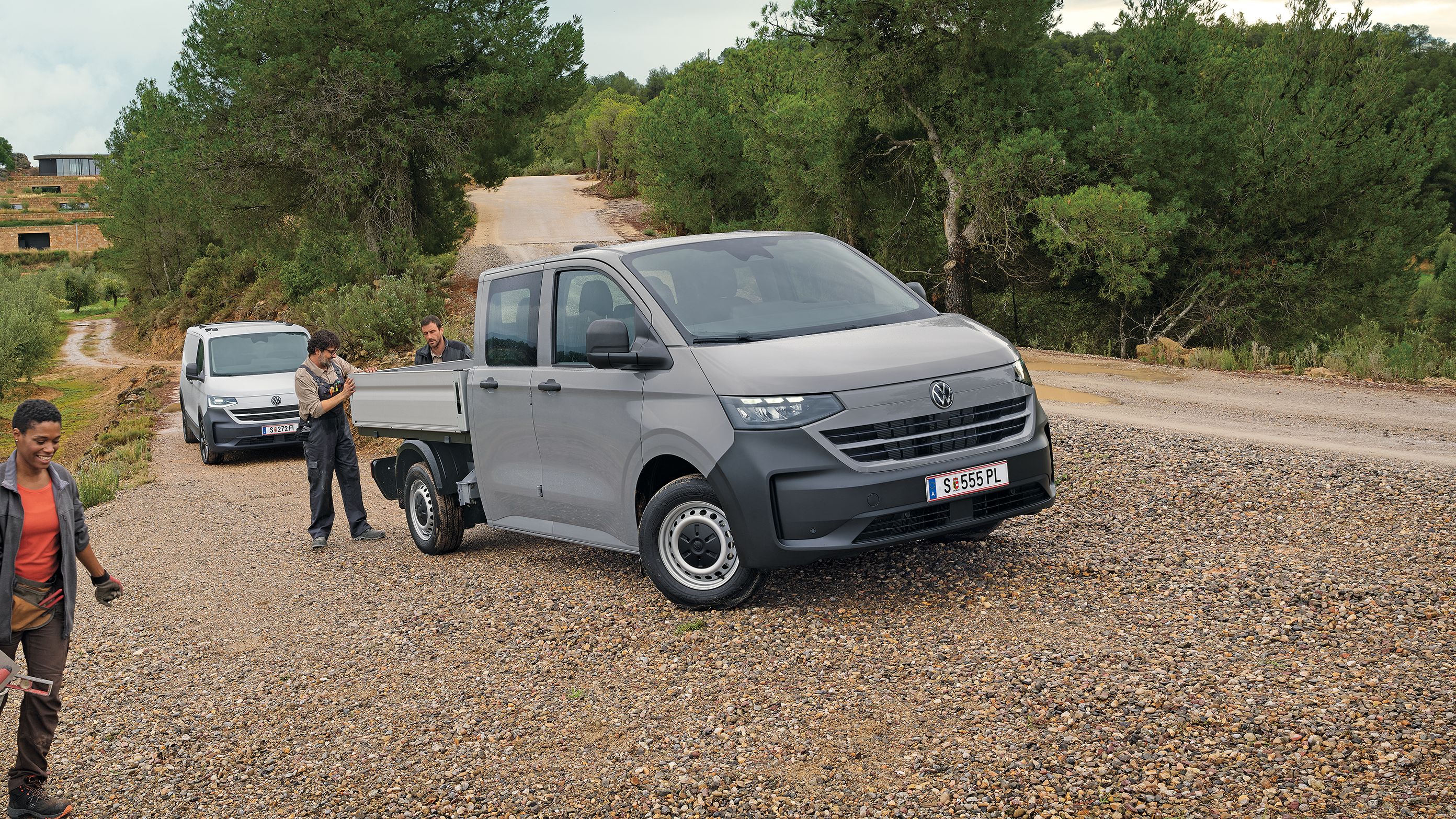 Volkswagen Transporter с двойна кабина на неасфалтиран терен с работници в работна среда