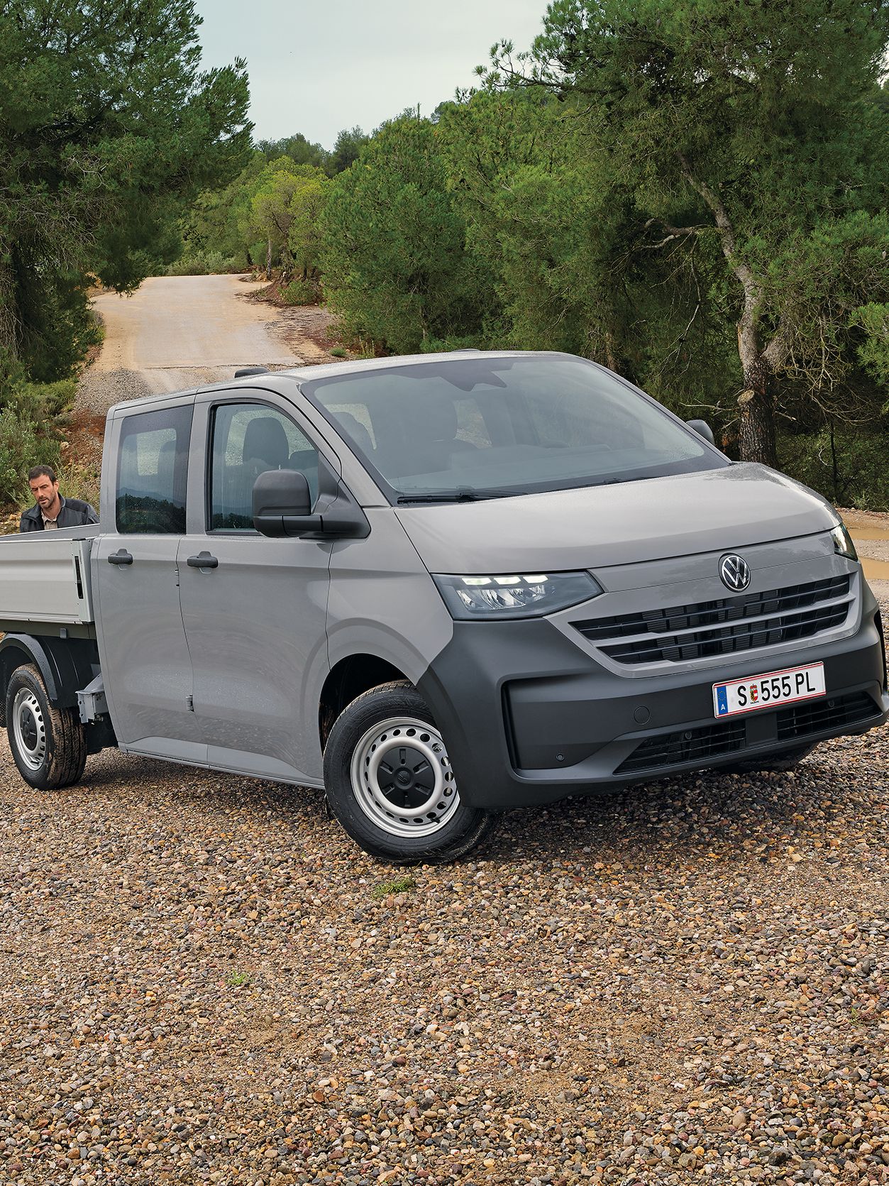 Volkswagen Transporter с двойна кабина на неасфалтиран терен с работници в работна среда