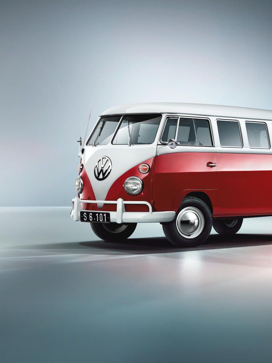 На изображението е показан ретро микробус Volkswagen в червено и бяло. Микробусът е паркиран на гладка, лъскава повърхност. Фонът е минималистичен, със сини и сиви нюанси.