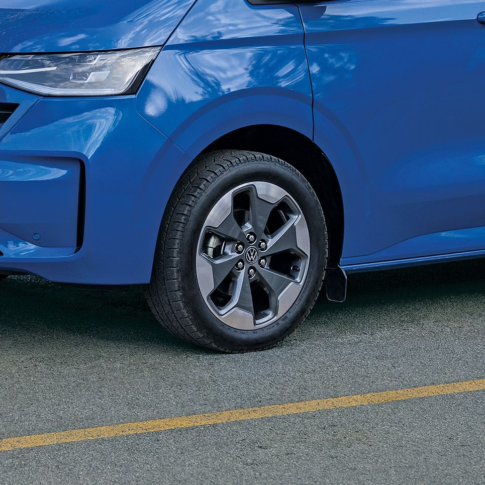 Мъж зарежда електрически Volkswagen Transporter, докато пътничка се качва в задната част на вана