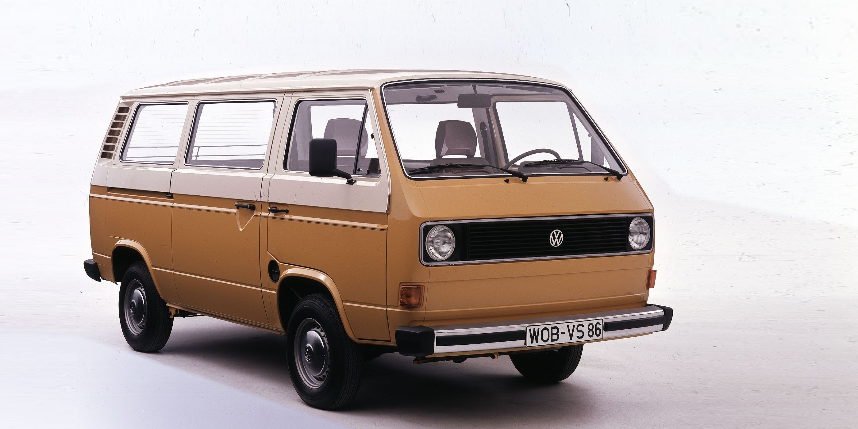 Класически ван, модел Volkswagen Transporter от 1970-те или 1980-те години, боядисан в жълто-кафяв цвят. Ванът има големи странични прозорци и бяла табела с регистрация.