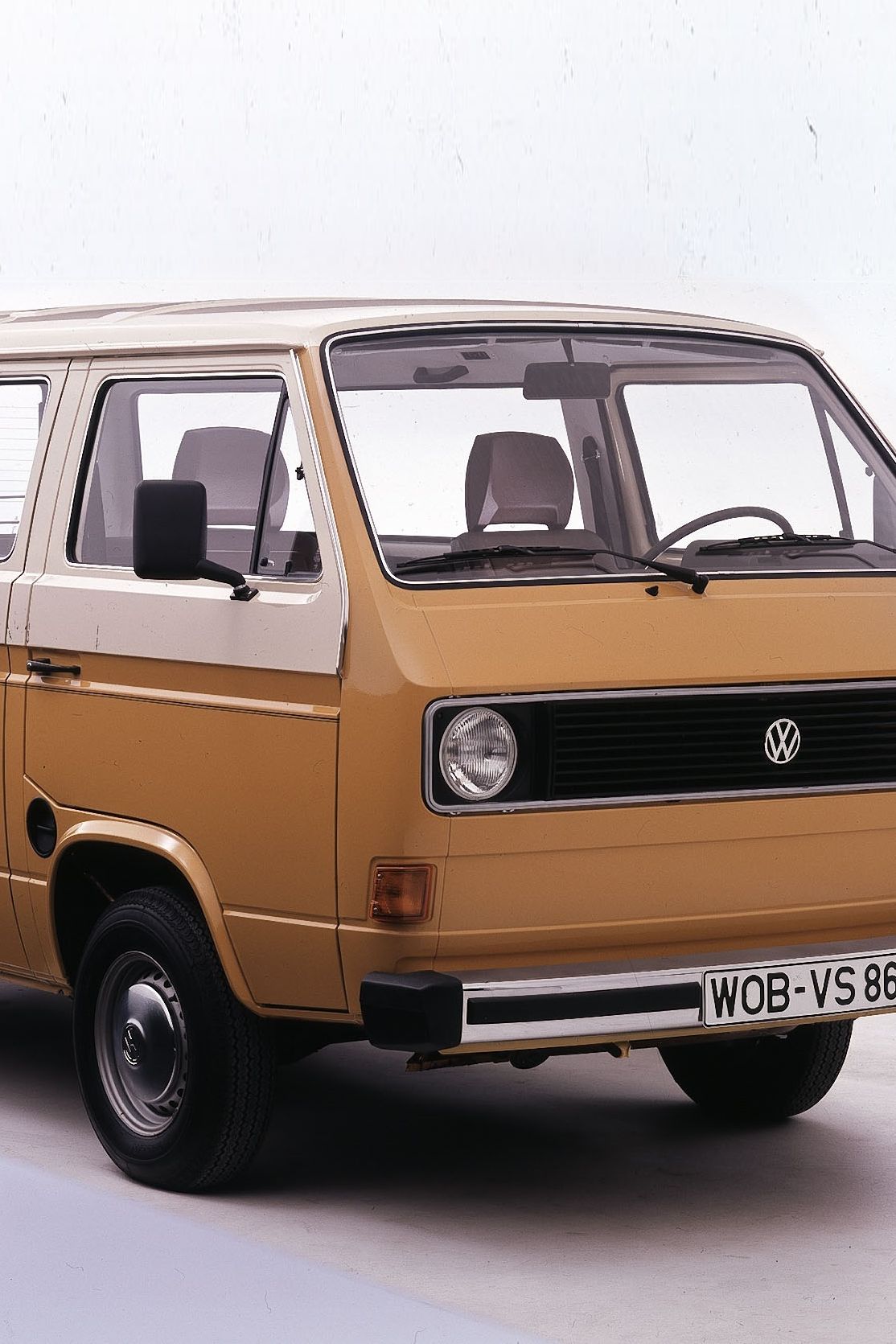 Класически ван, модел Volkswagen Transporter от 1970-те или 1980-те години, боядисан в жълто-кафяв цвят. Ванът има големи странични прозорци и бяла табела с регистрация.