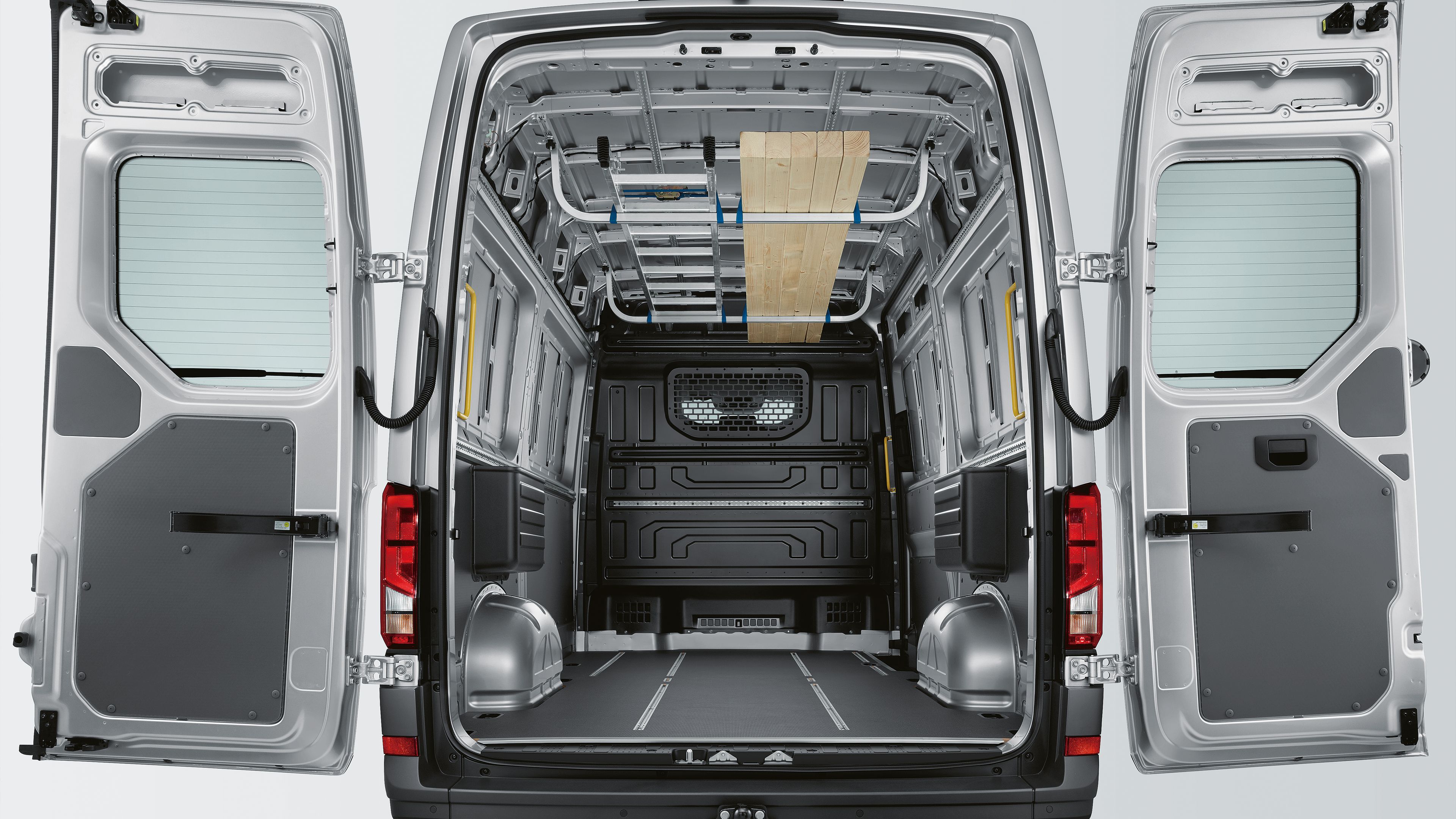 Заден изглед към празно товарно пространство на Volkswagen Crafter с дървена облицовка и метален под.