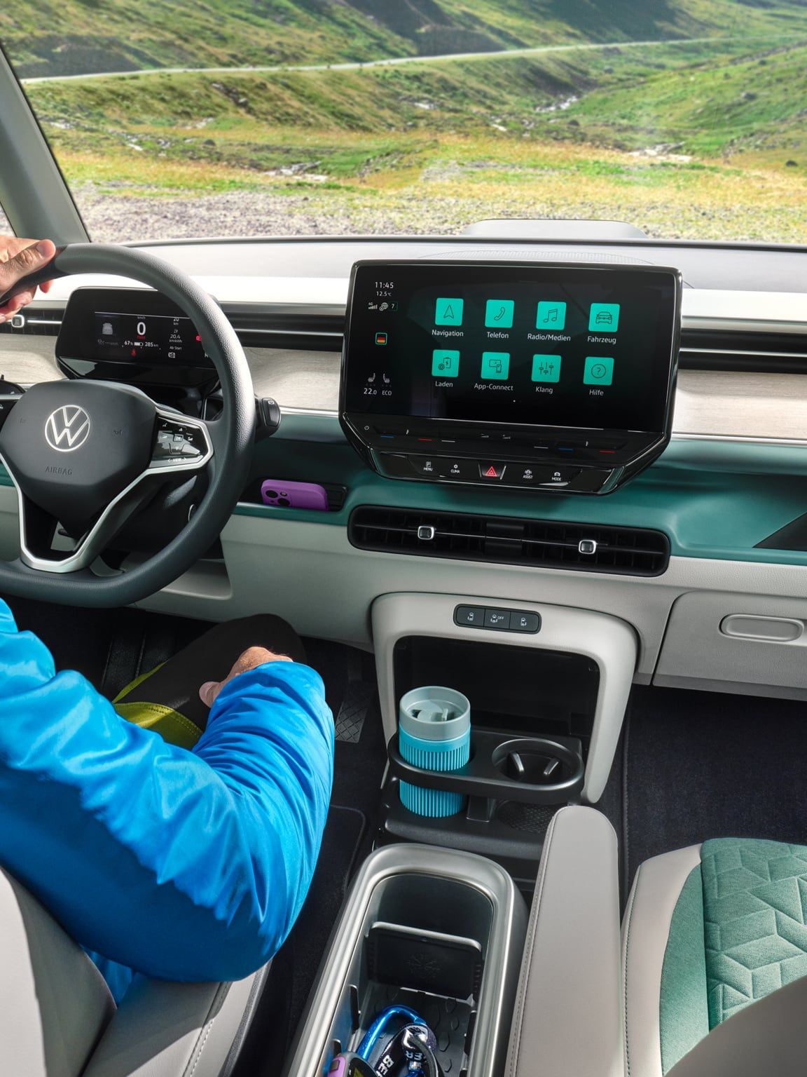 Интериор на Volkswagen ID. Buzz с водач и дигитален кокпит, подлакътник с поставка за вещи и изглед към планински пейзаж