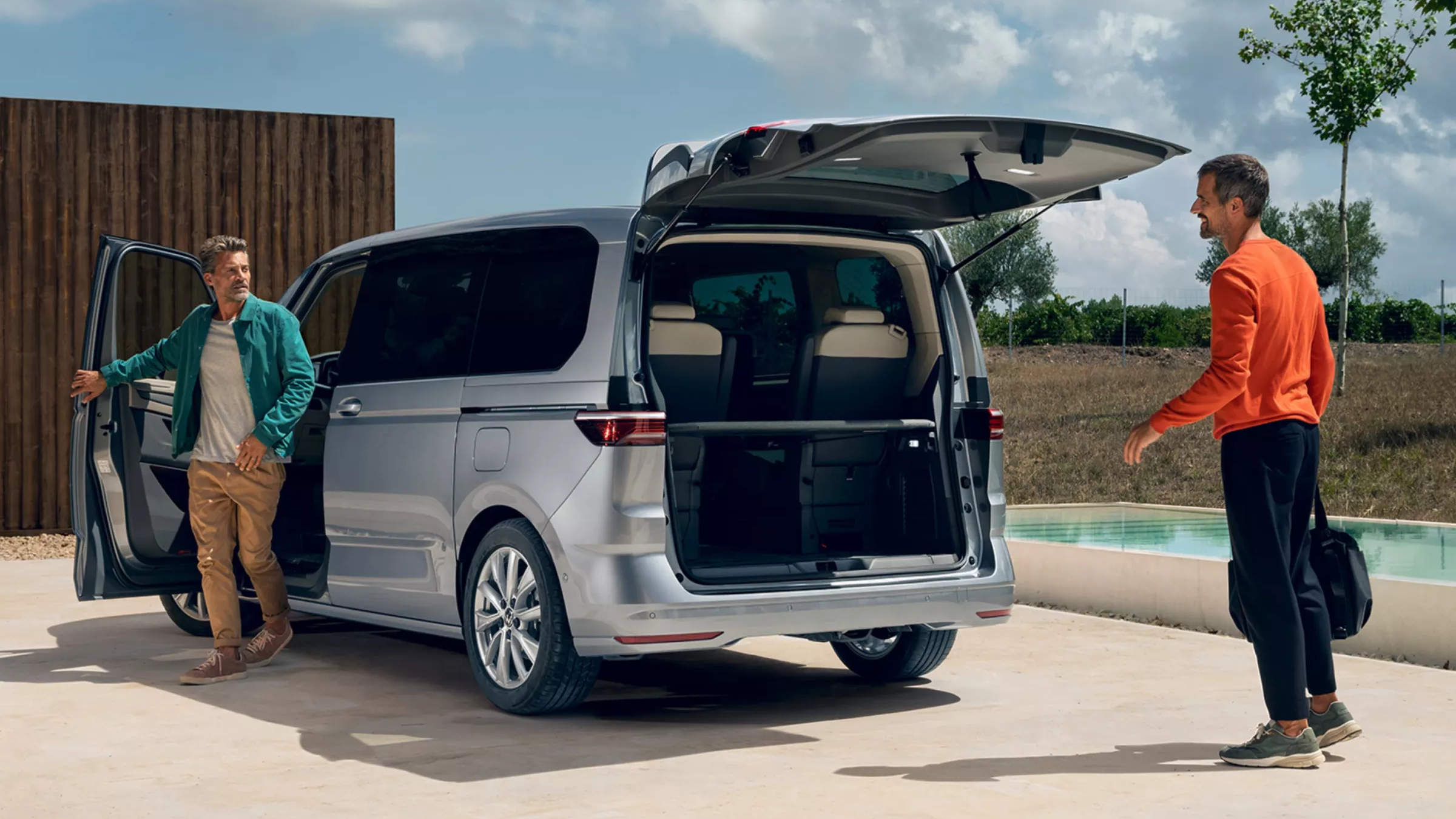 Ein Mann schließt die Fahrertür des neuen VW Multivan, ein anderer Mann wartet hinter dem Auto