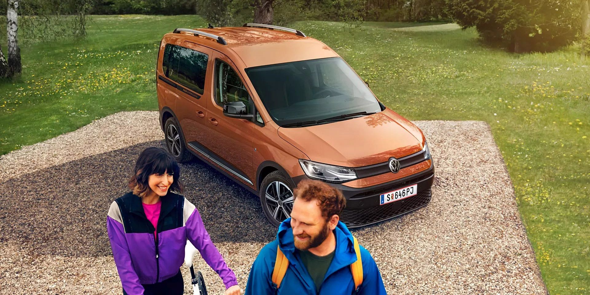 Caddy Alltrack е спрял край черен път. Зад него има гориста планинска местност.