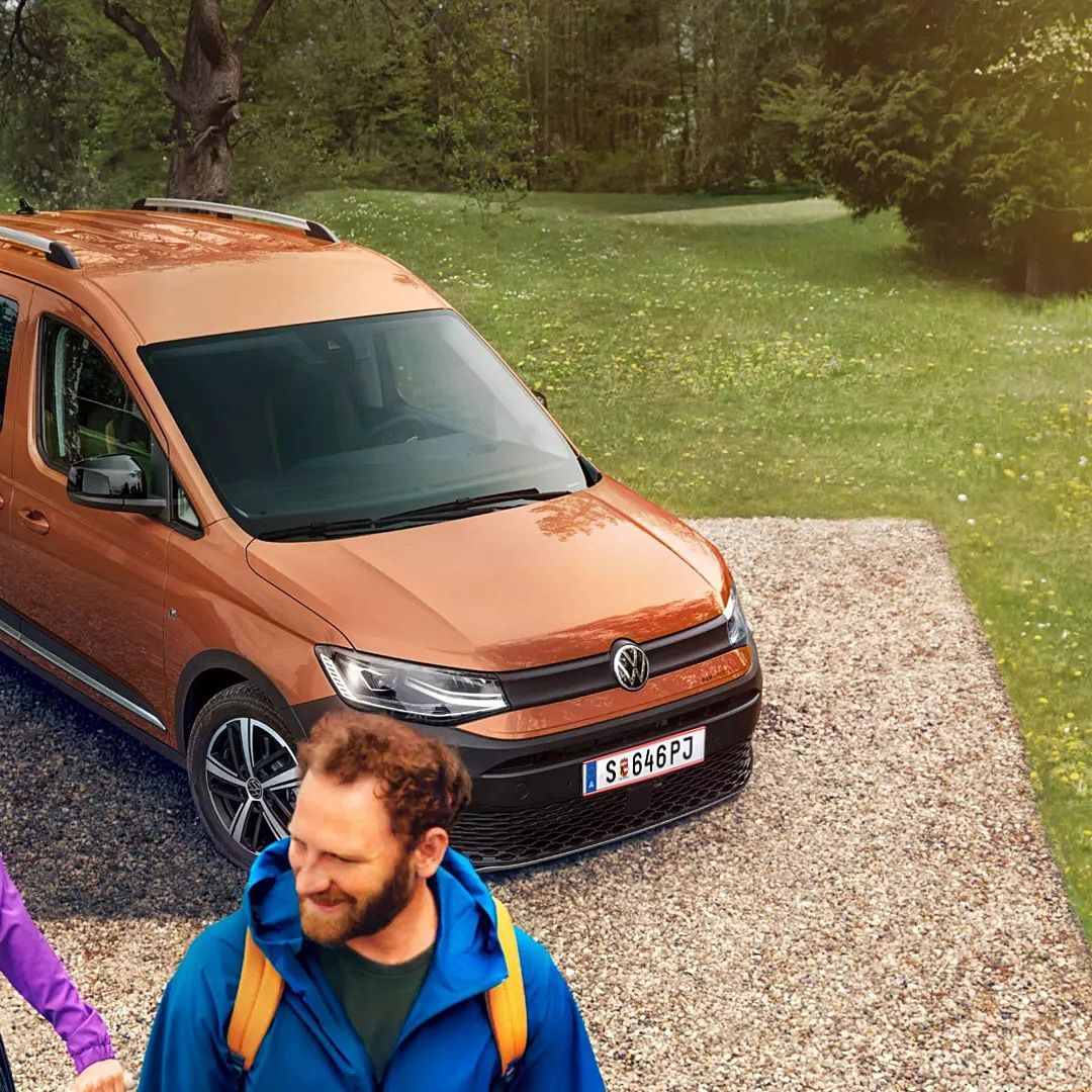 Caddy Alltrack е спрял край черен път. Зад него има гориста планинска местност.