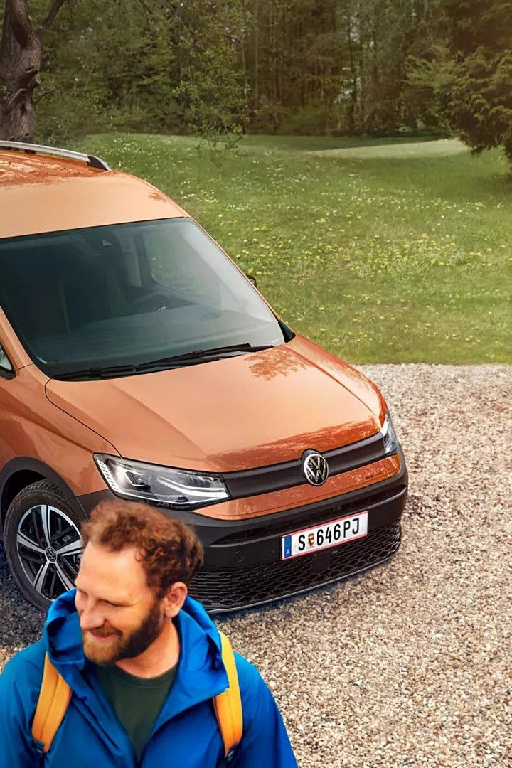Caddy Alltrack е спрял край черен път. Зад него има гориста планинска местност.