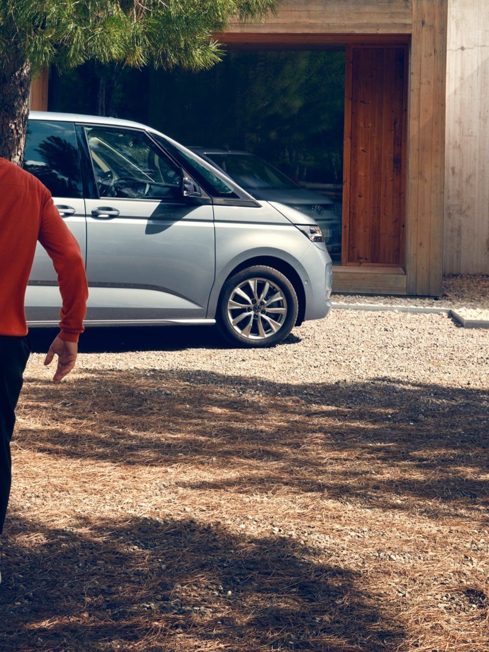 Zwei Männer laufen auf einen silbernen neuen VW Multivan T7 2021 zu.