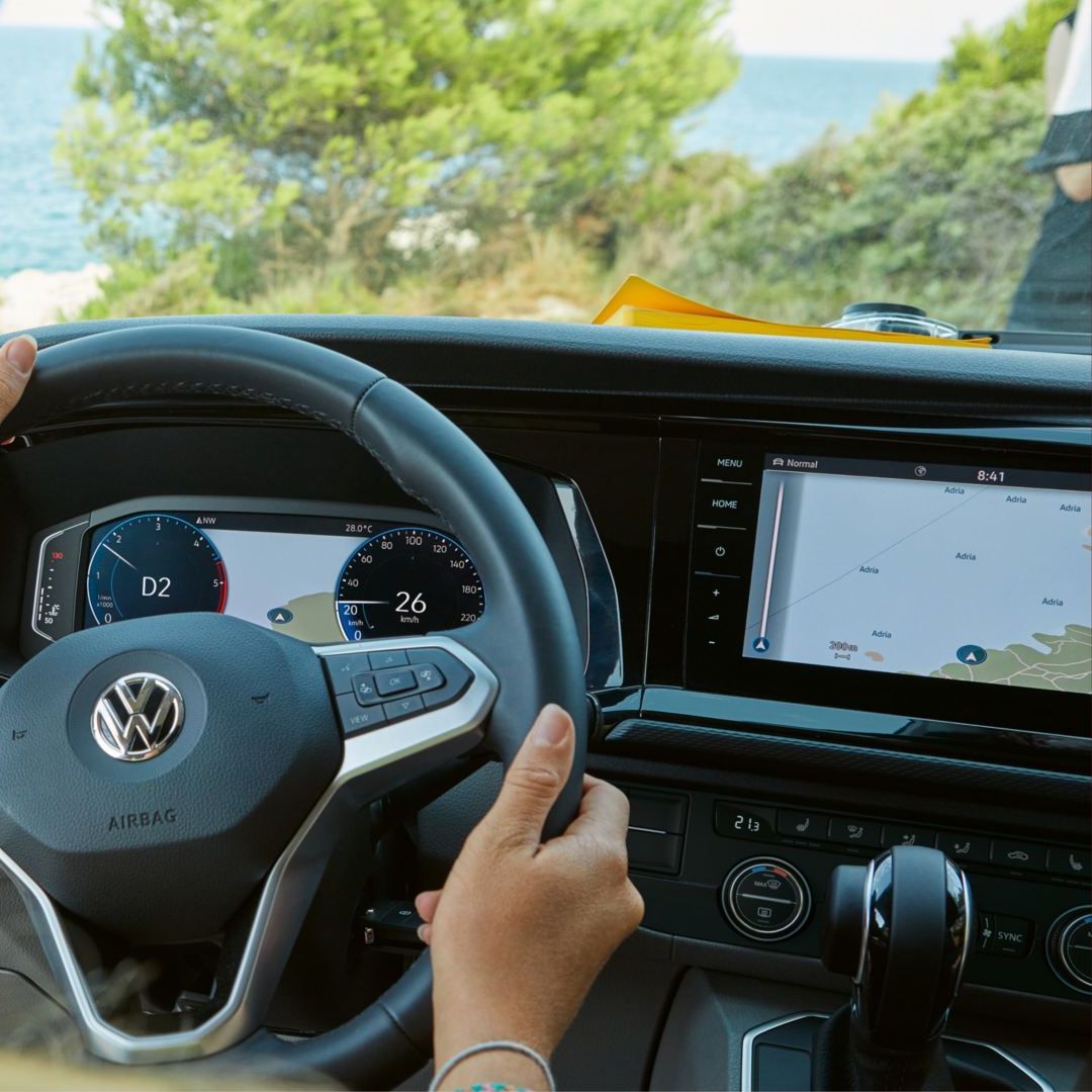Шофиране на Volkswagen с изглед към морето и дигитална навигация на таблото