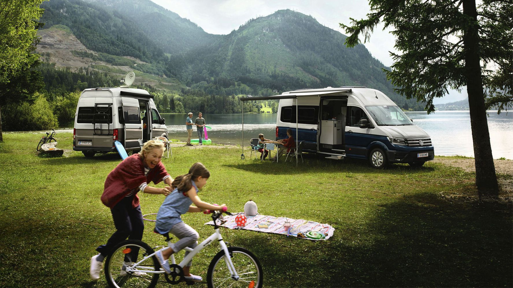 Zwei VW Grand California stehen vor einem See