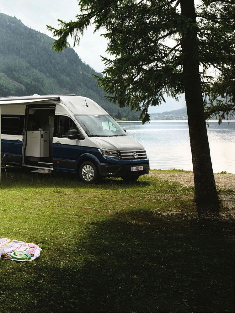 Zwei VW Grand California stehen vor einem See 