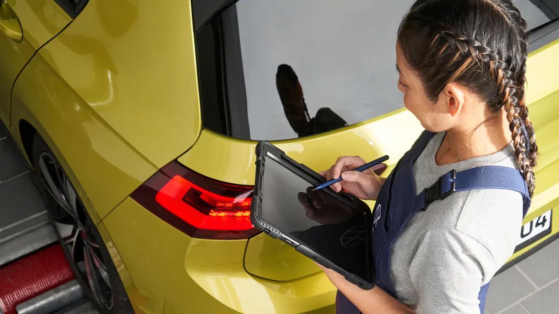 Сервизен техник на Volkswagen проверява автомобил с таблет.
