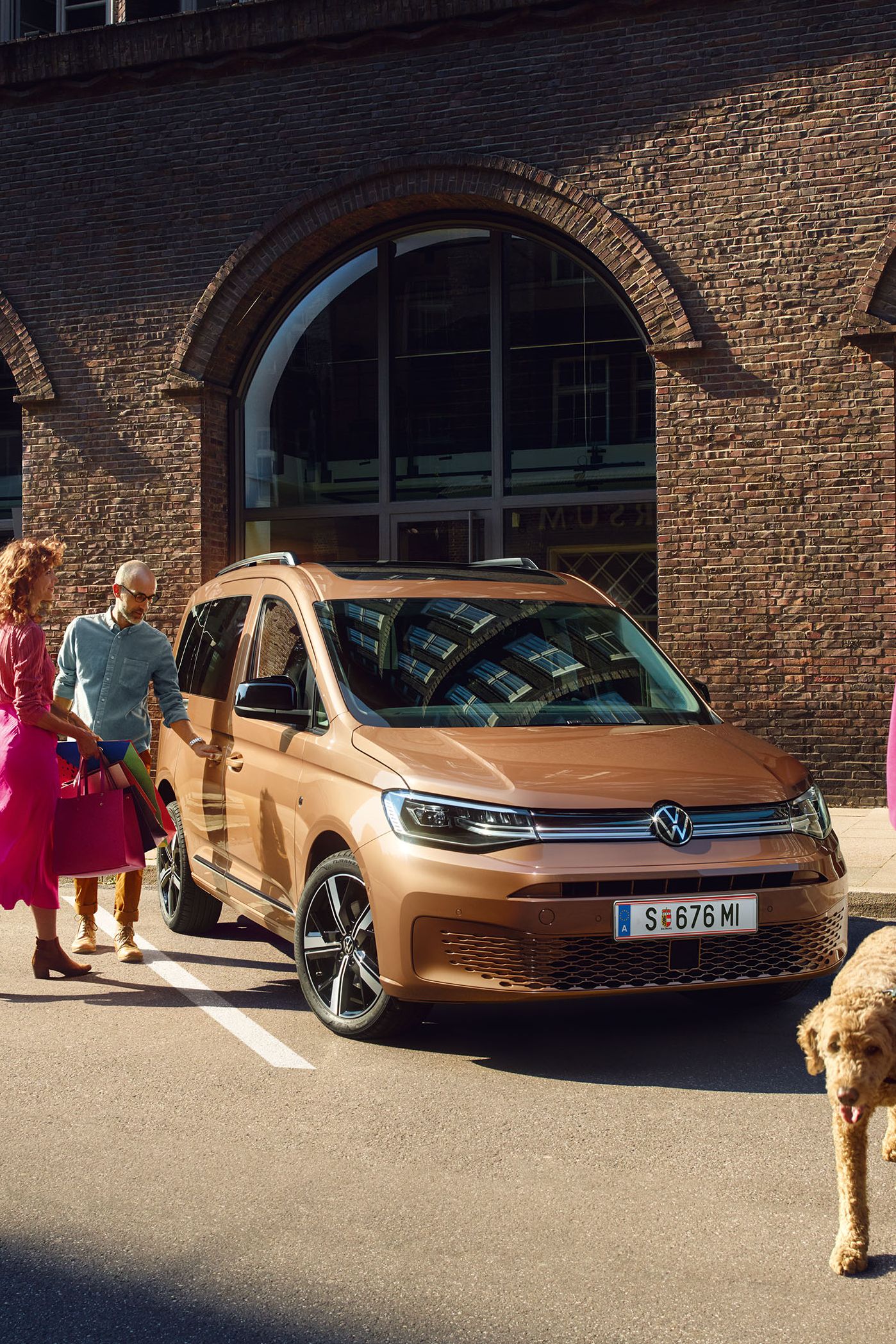 VW Caddy Cargo in Weiß steht auf Straße und Mann steht davor