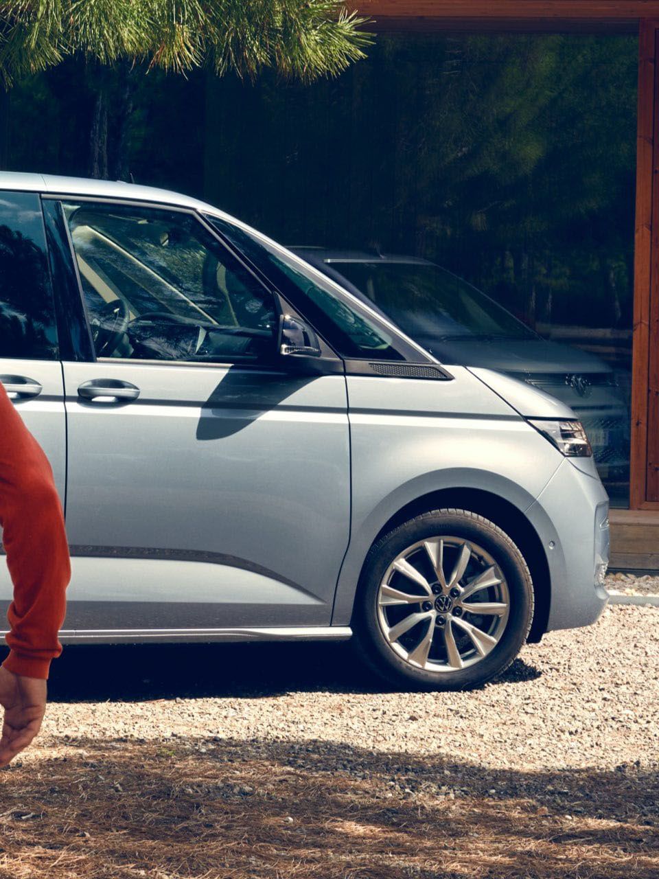 Zwei Männer laufen lachend auf den neuen VW Multivan Life T7 2021 zu.