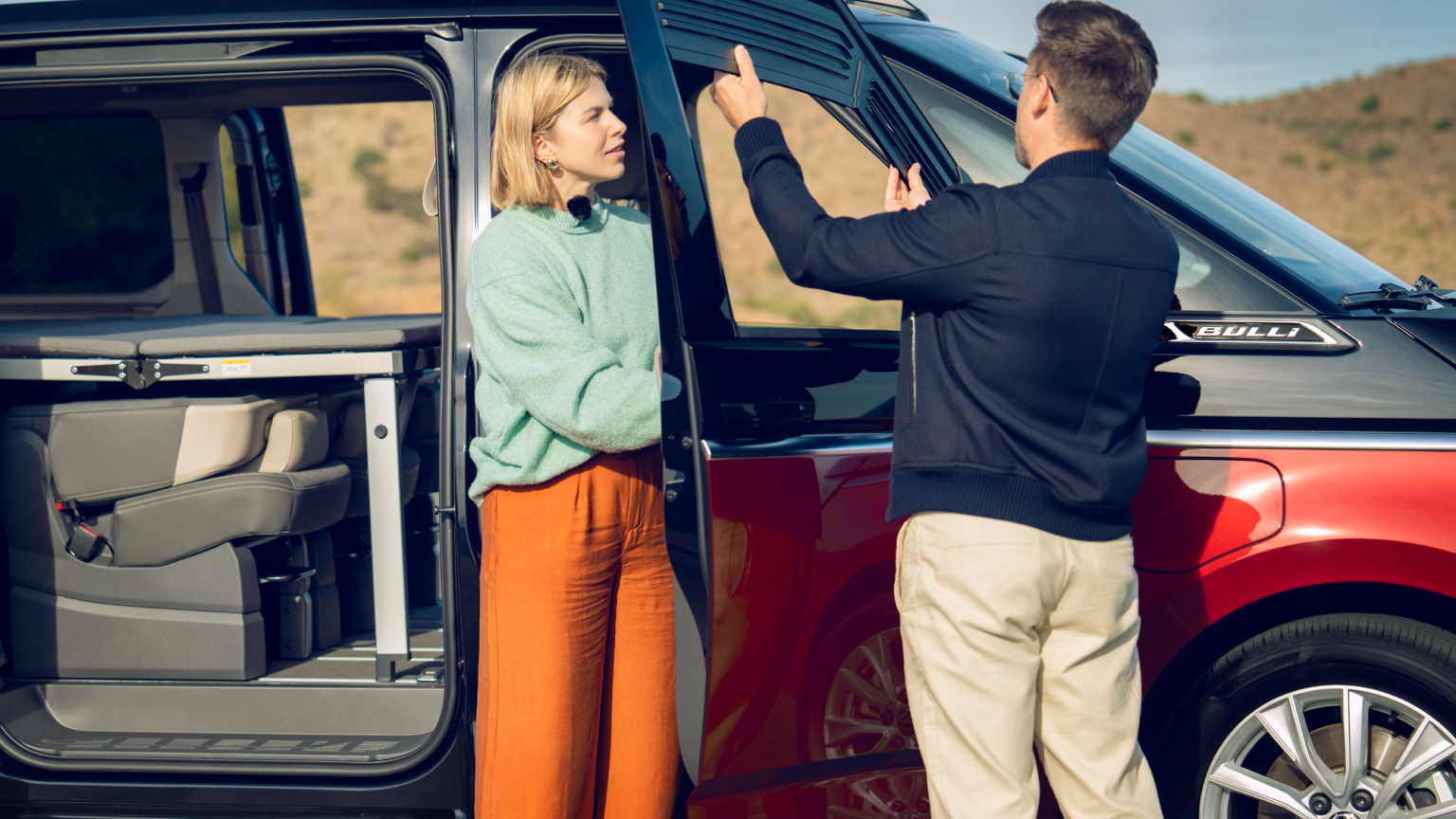 Мъж и жена монтират сенник на прозореца на Volkswagen Multivan