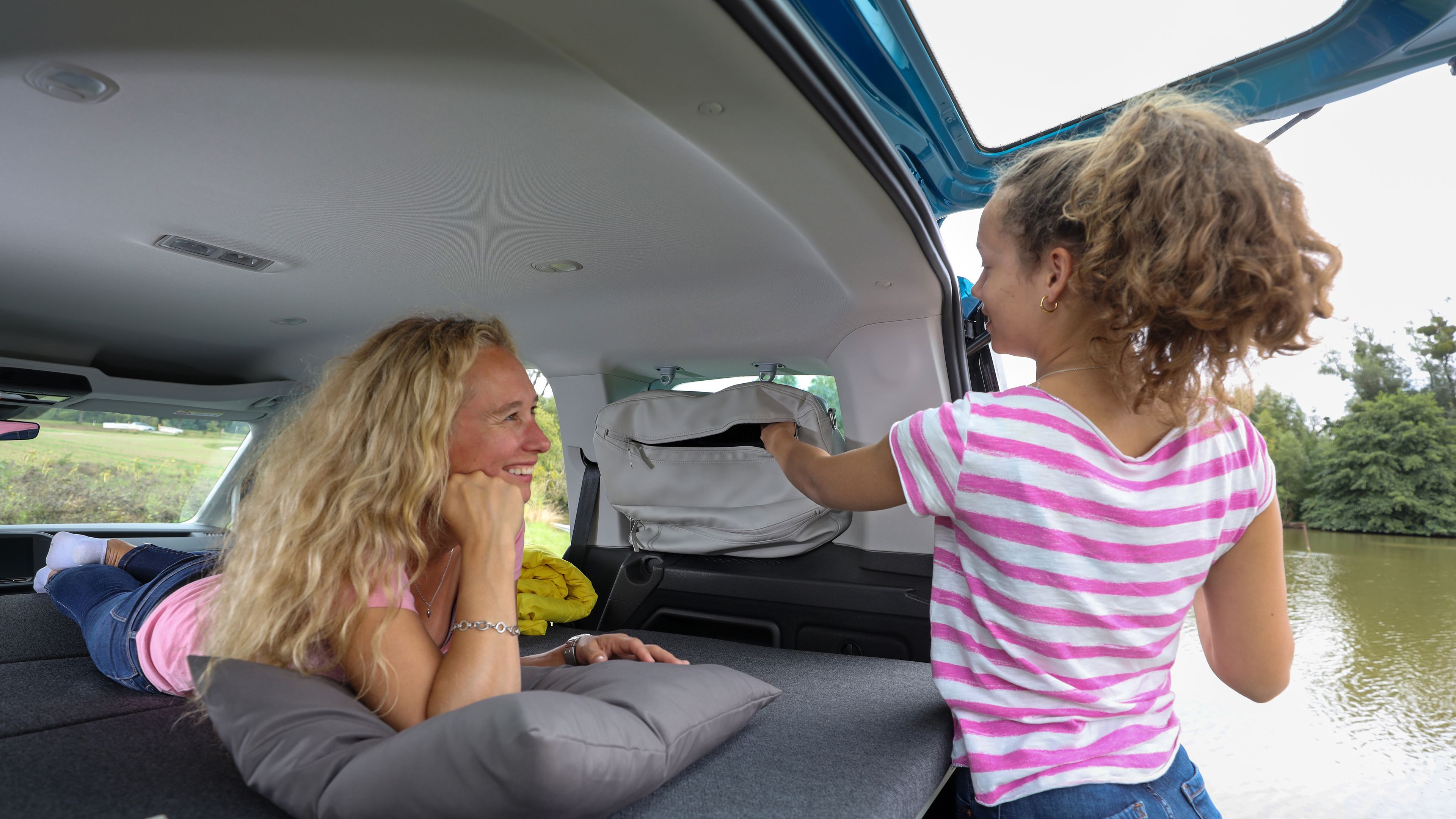 Frau liegt auf Bett von Caddy California und Kind montiert Stautasche ab.